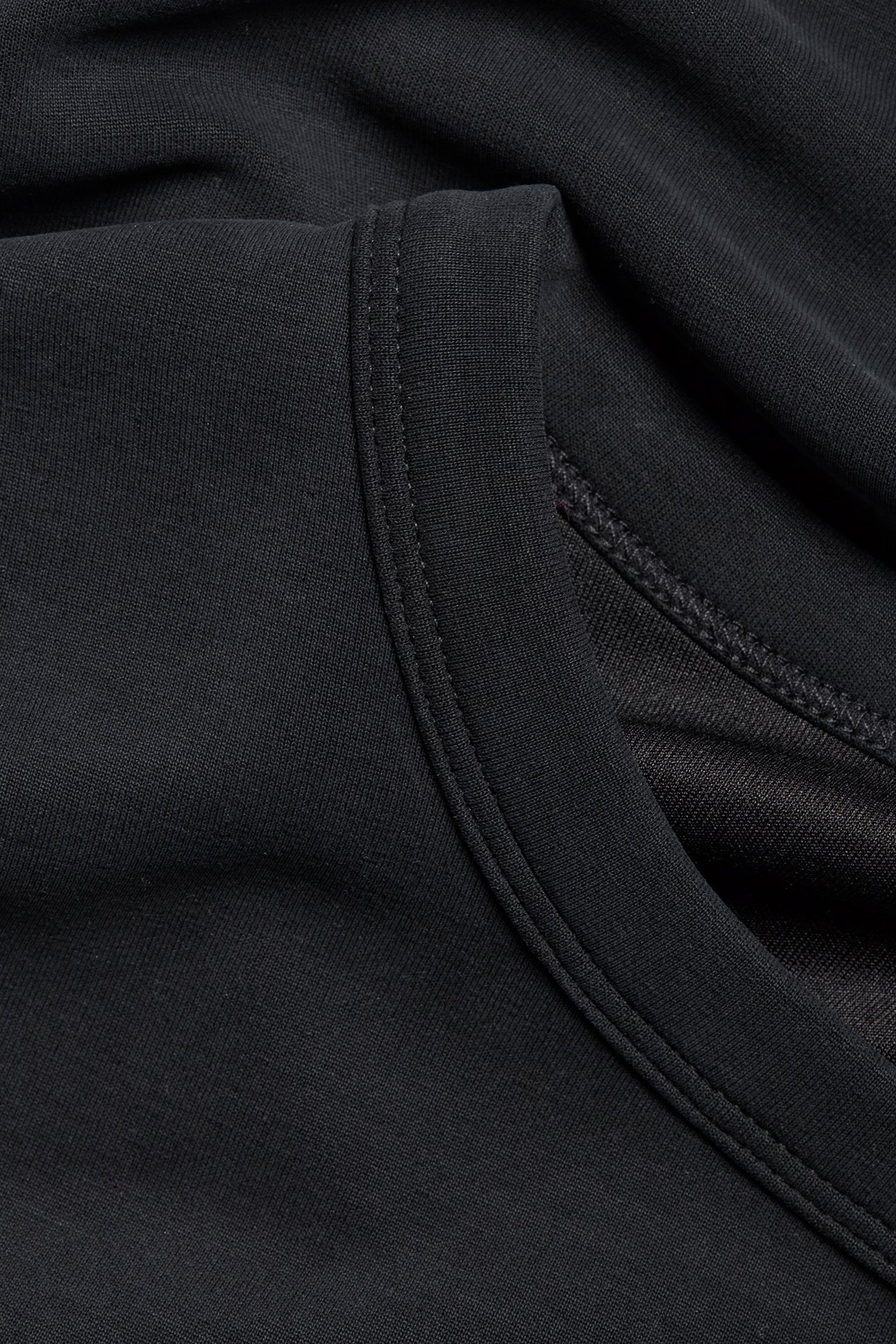 Zbliżenie czarnego T-shirtu, ukazujące miękką fakturę materiału i wykończony dekolt.