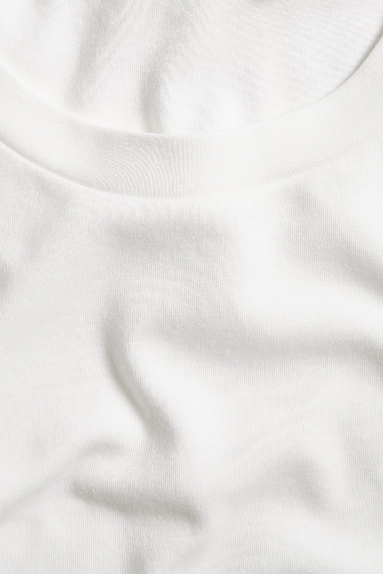 Zbliżenie na biały, oversize'owy bawełniany t-shirt z okrągłym dekoltem.