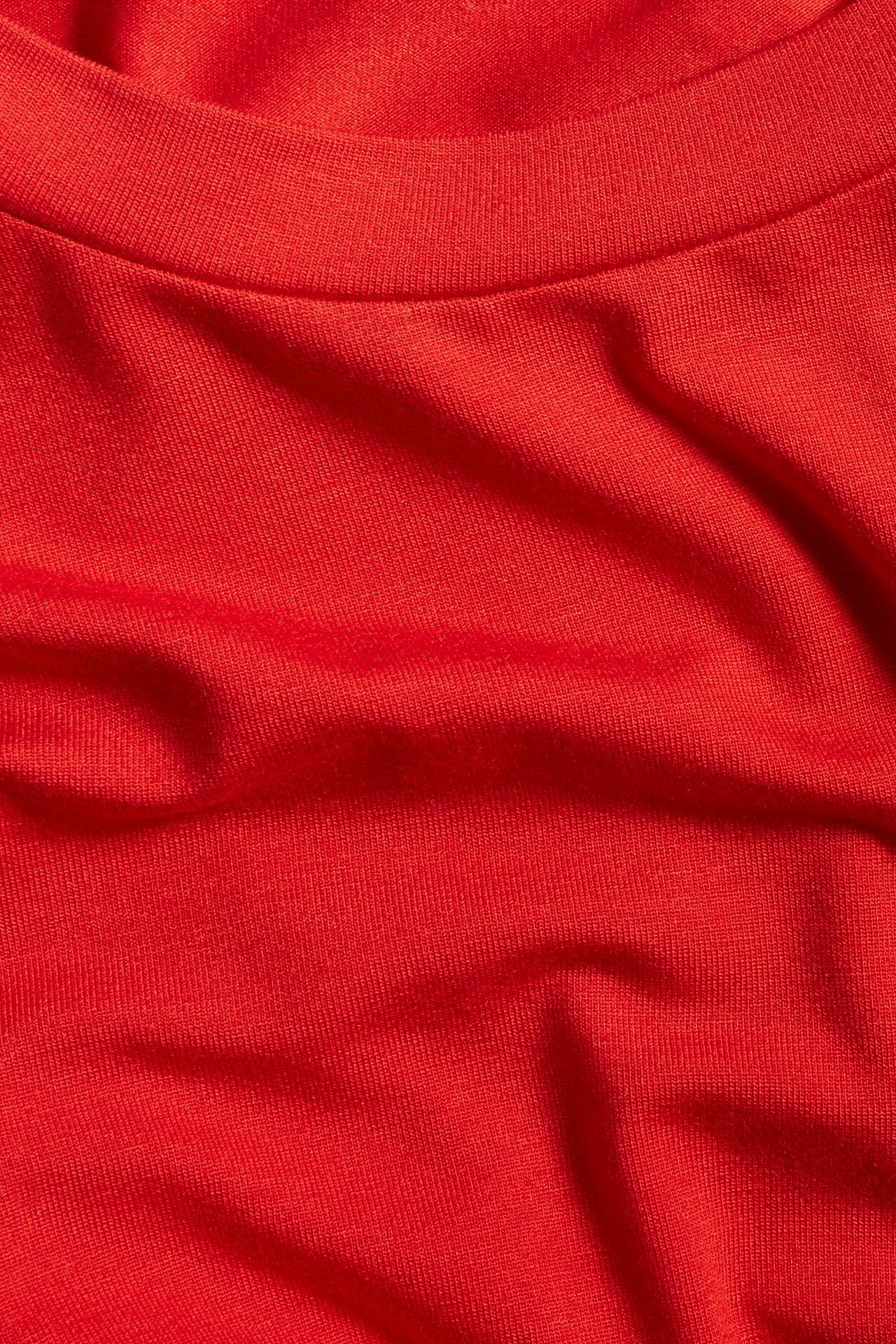Zbliżenie czerwonego, dopasowanego t-shirtu z półgolfem, wykonanego z mieszanki wiskozy.