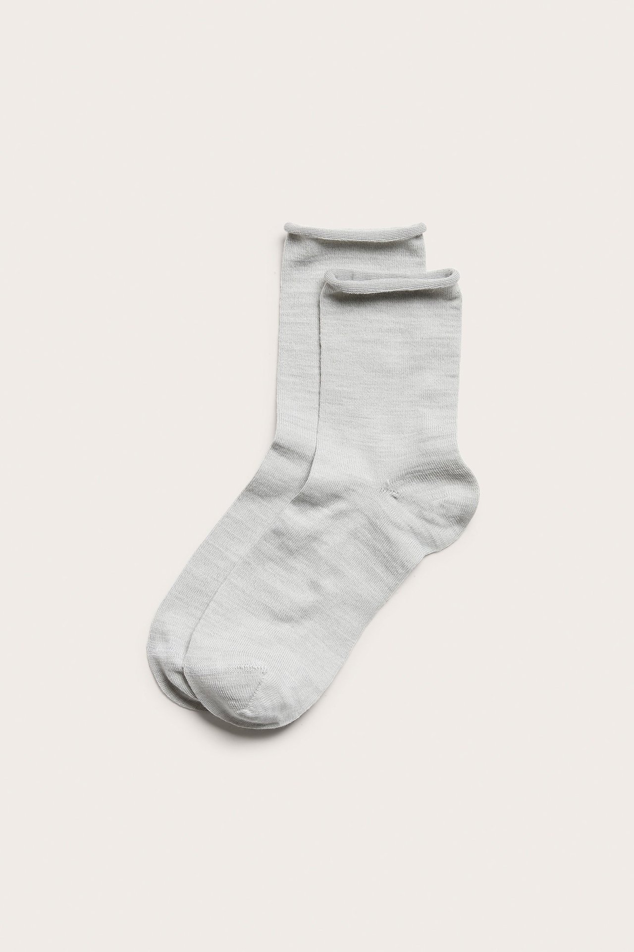 Widok z góry na parę kremowych skarpet z mieszanki wełny z rolowanym mankietem.