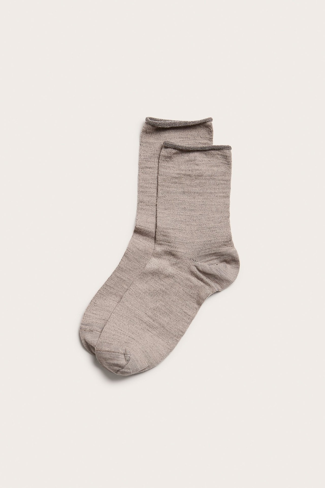 Widok z góry na parę beżowych melanżowych skarpet z mieszanki wełny z rolowanym brzegiem.