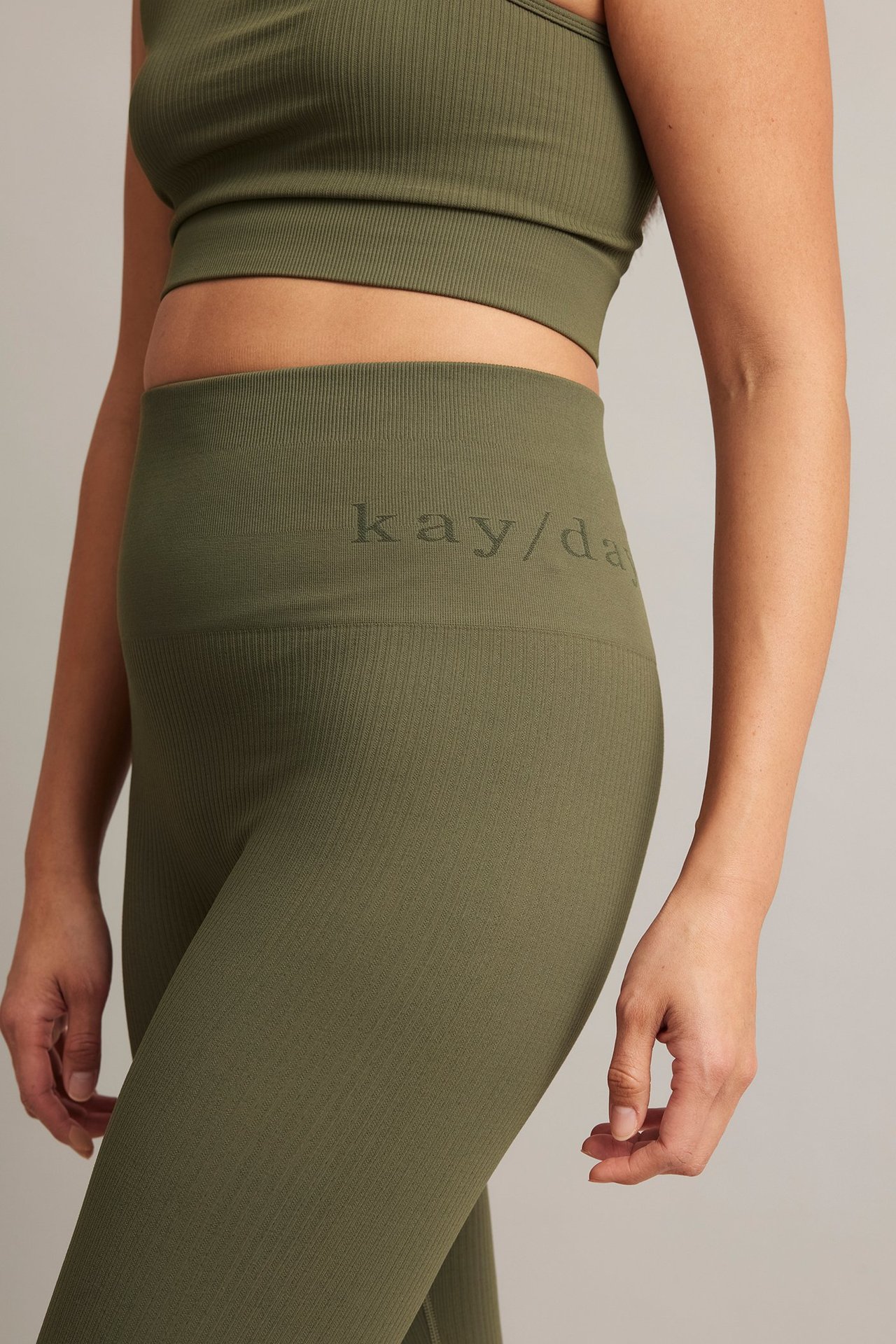 Närbild framifrån på en kvinna i gröna ribbade träningstights med matchande sport-bh.