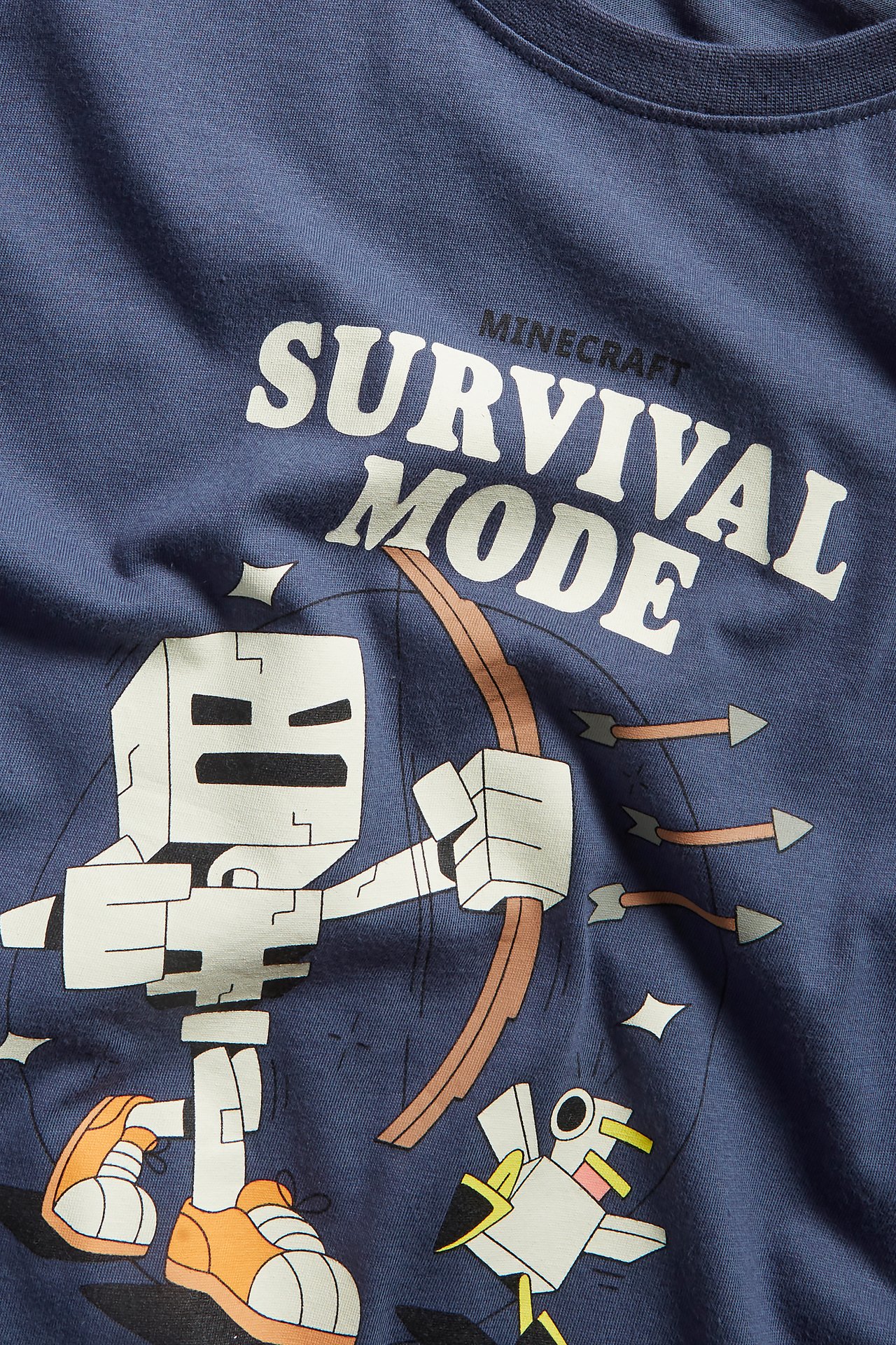 Zbliżenie na niebieską bawełnianą koszulkę dziecięcą z nadrukiem Minecraft: szkielet i "Survival Mode".