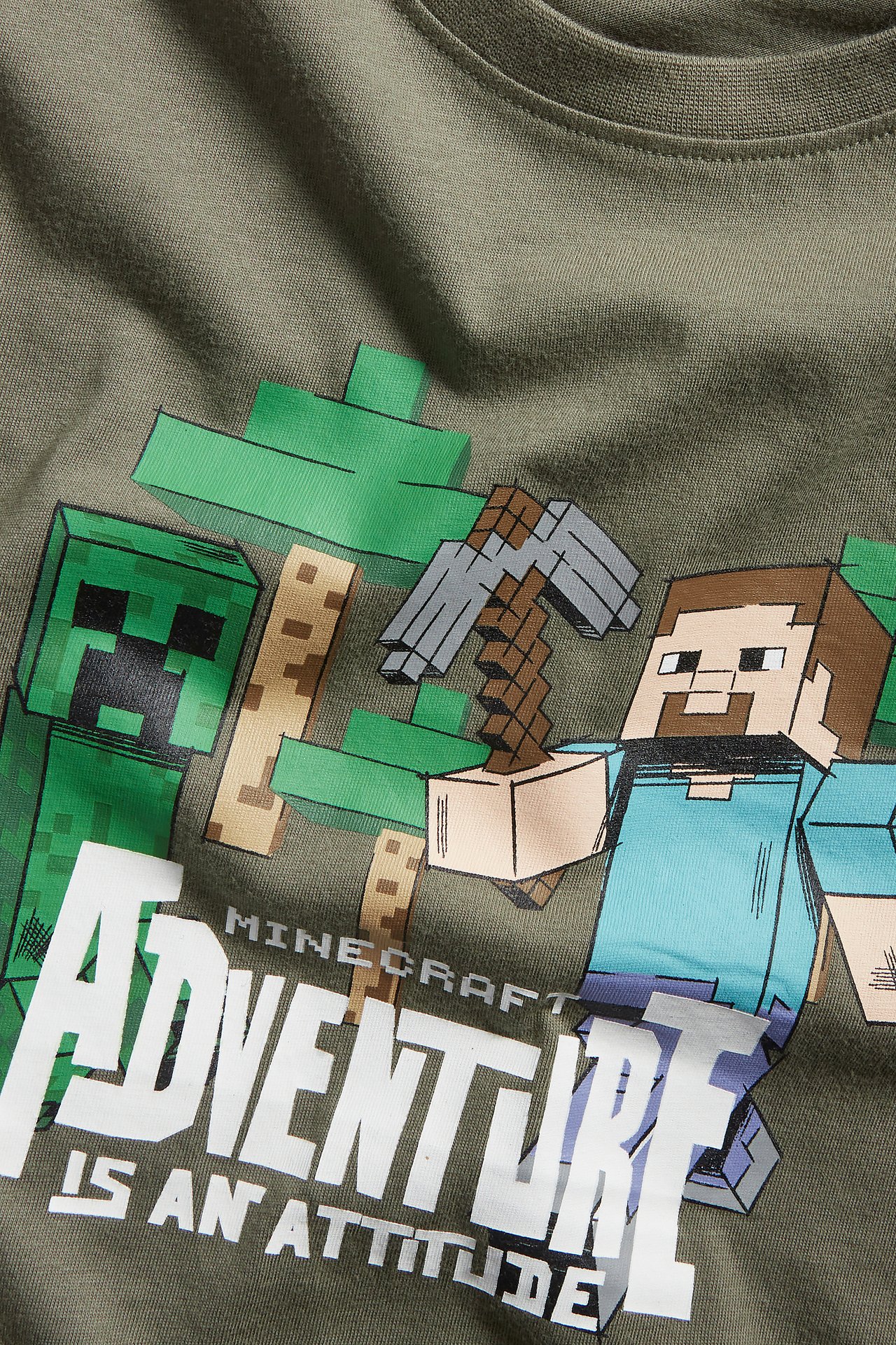 Zbliżenie na zielony bawełniany t-shirt dziecięcy z kolorowym nadrukiem Minecraft z przodu.