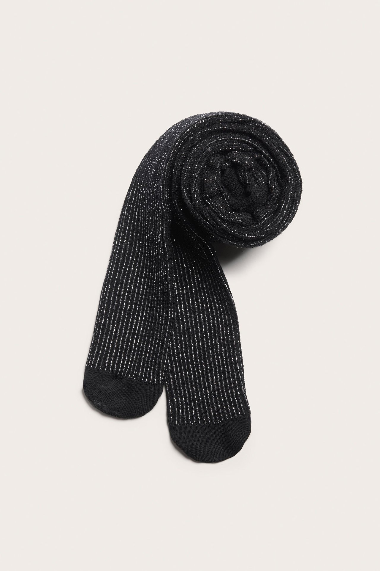 Ylhäältä kuvattuina: mustat puuvillasekoitesukkahousut hopeaglitterraidoilla, rullattuina.