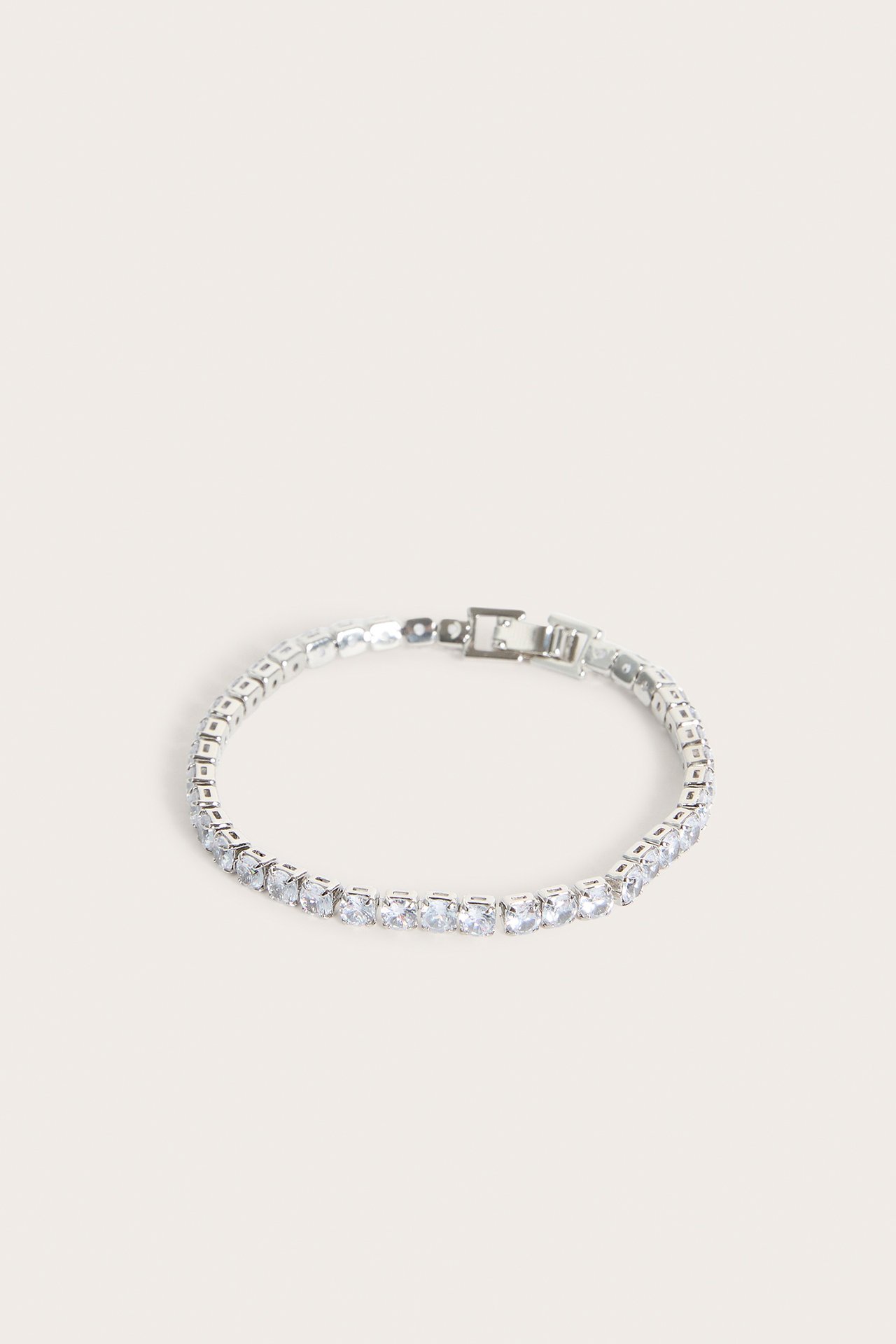 Närbild av ett silverfärgat armband med klara strassstenar och synligt lås.