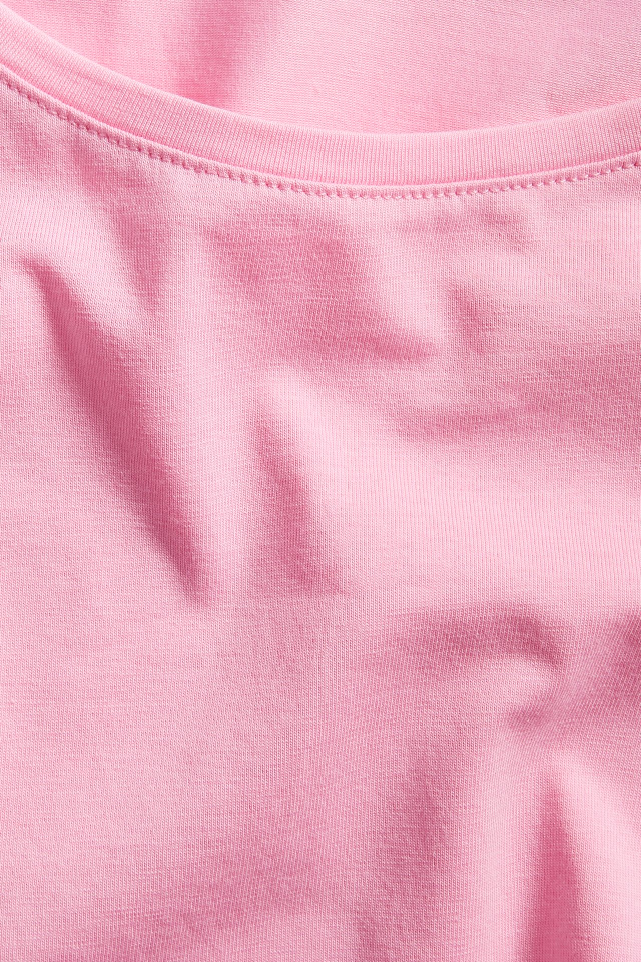 Närbild av en rosa långärmad bastopp med rundhals i bomullsblandning.
