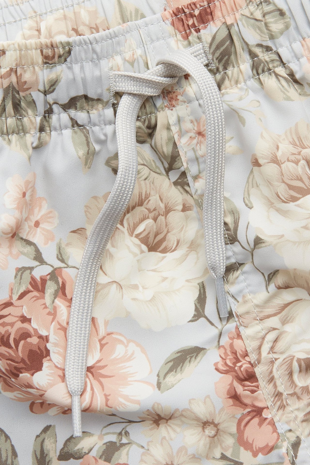 Närbild av blå blommiga badshorts med resårlinning och ljusgrå dragsko.