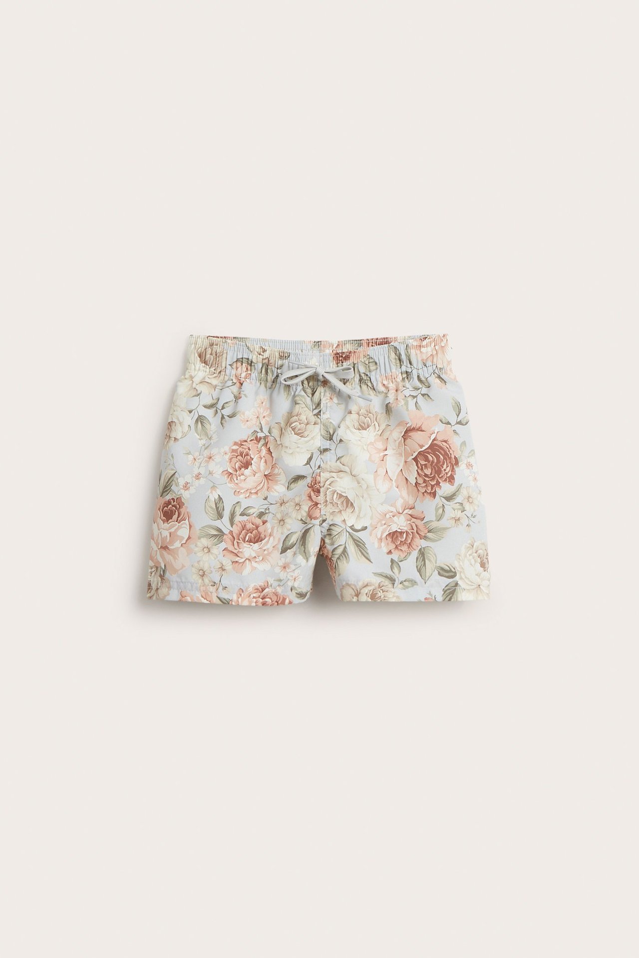 Frontvy av barnens ljusblå blommiga badshorts med resår i midjan och dragsko.