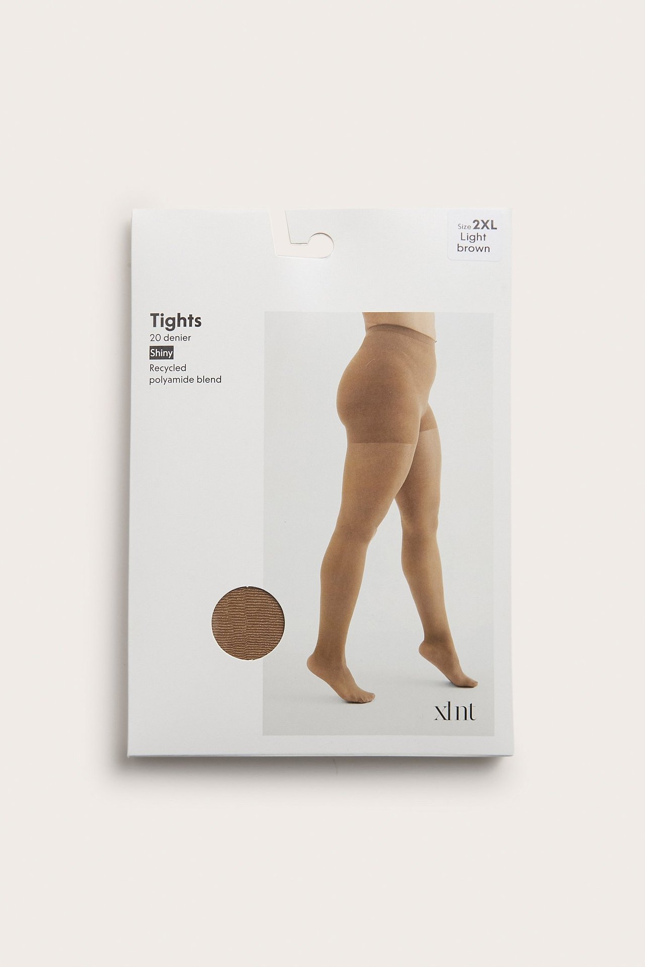 Sivukuva naisen jaloista yllään vaaleanruskeat, kiiltävät 20 denierin sukkahousut, esitetty pakkauksessa.
