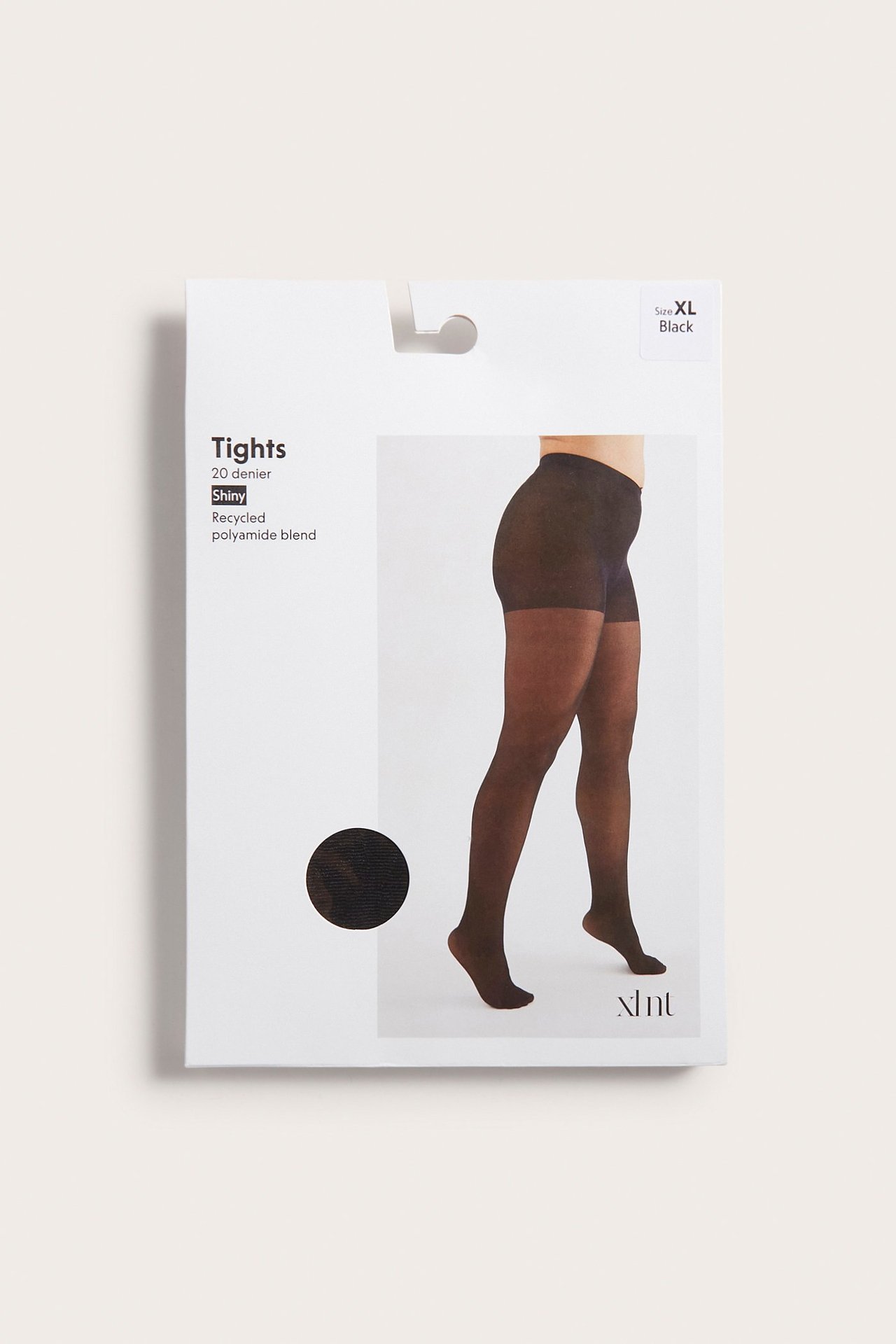 Widok z boku kobiety w czarnych, błyszczących rajstopach 20 denier z mieszanki poliamidu.