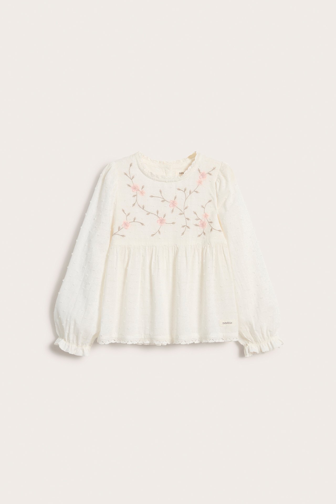 Frontvisning: Offwhite vevd bomullsbluse for barn med rosa blomsterbroderi, strukturprikker, puffermer, blondekant.