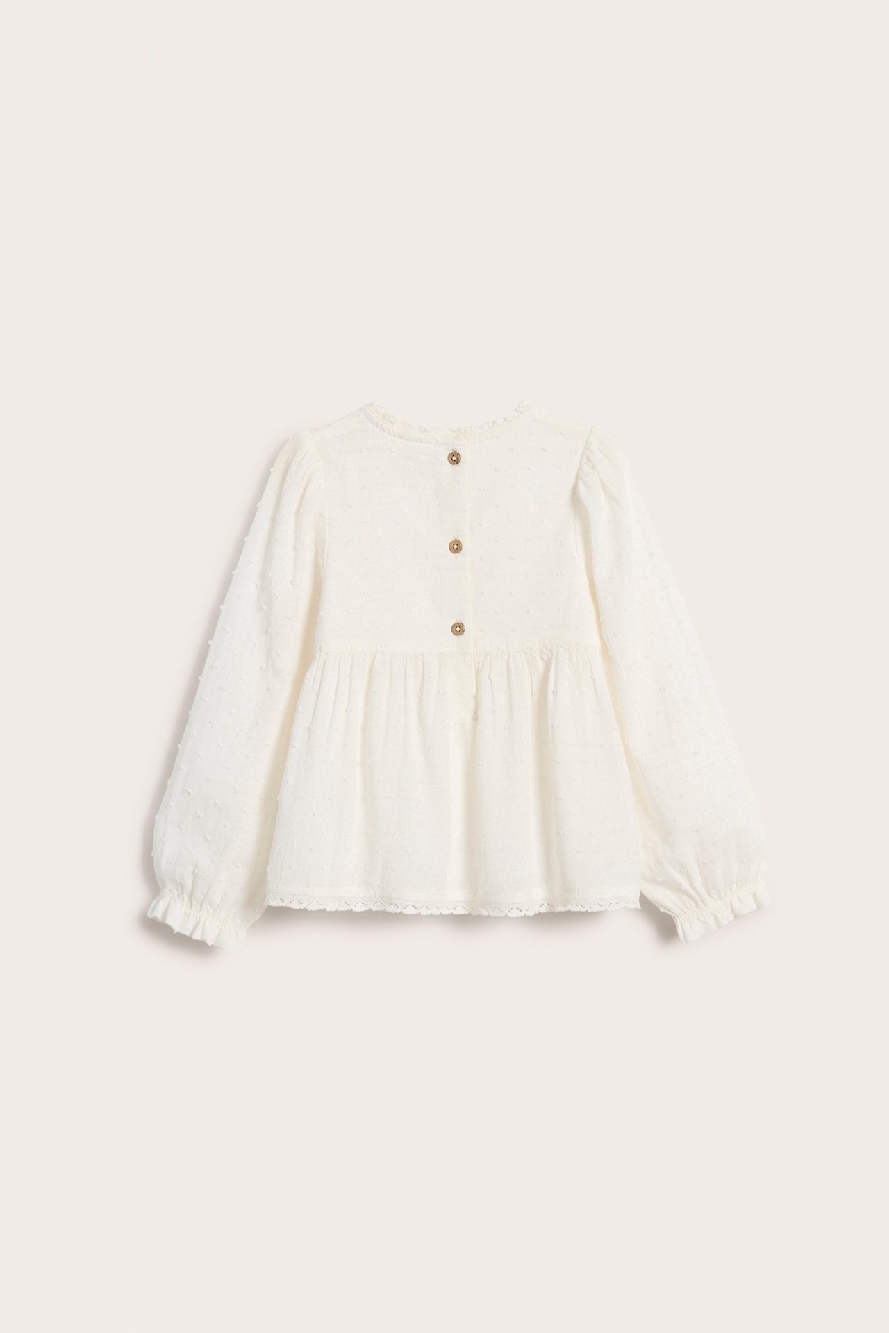 Bakfra: Offwhite vevd barnebluse i bomull med strukturprikker, puffermer, blondekant og knapper bak.