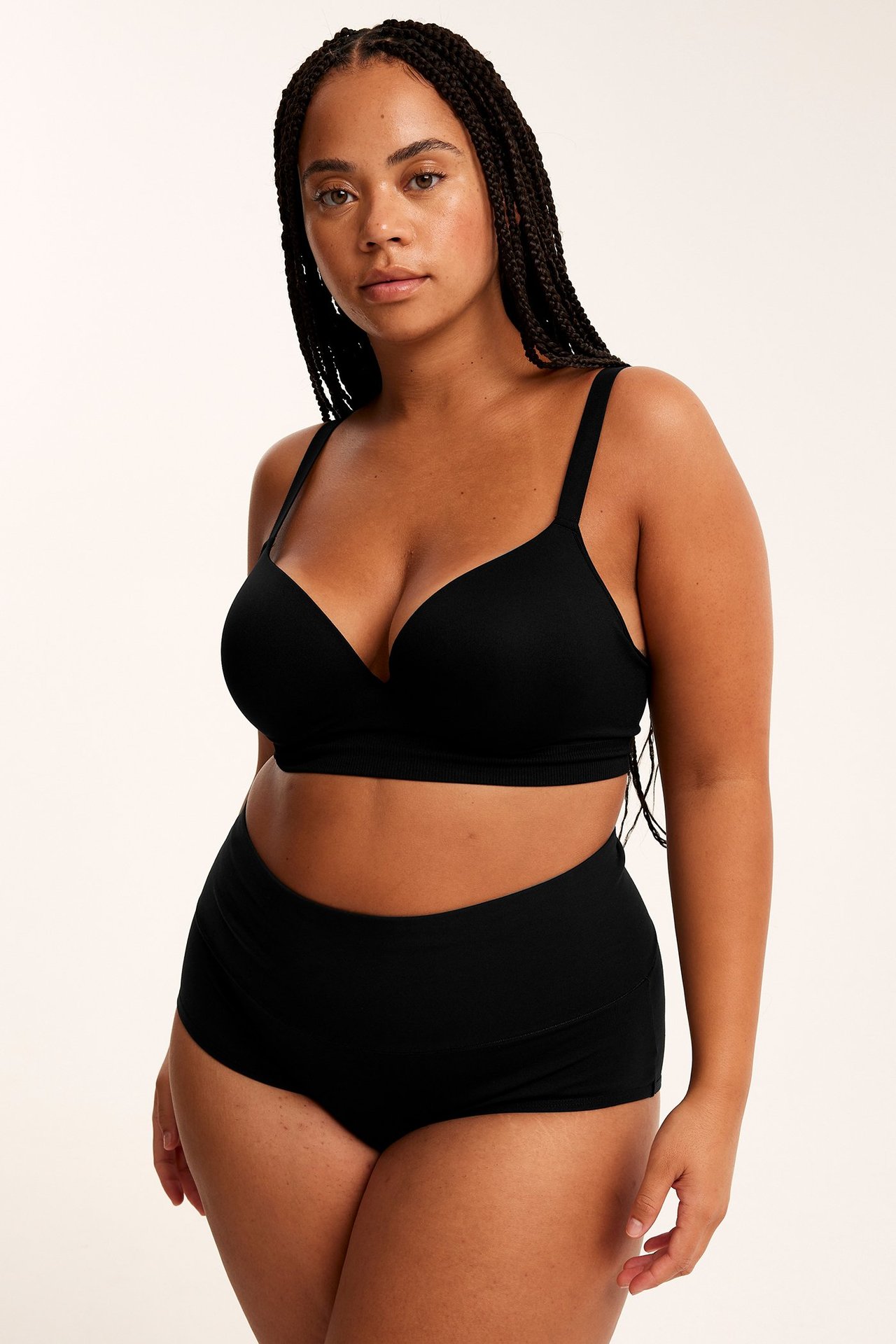 Widok z przodu kobiety w czarnych bawełnianych figach hipster z szerokim pasem i czarnym biustonoszu.