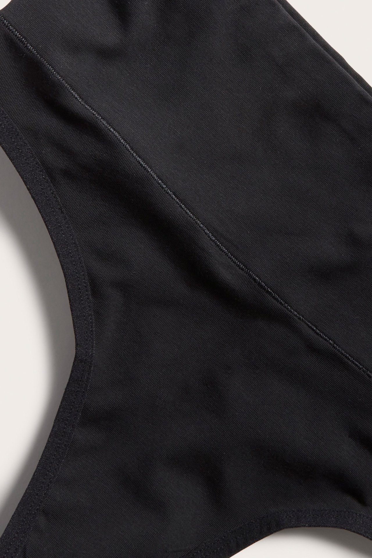 Zbliżenie czarnych, miękkich bawełnianych stringów z widocznymi szwami i szerokim pasem.