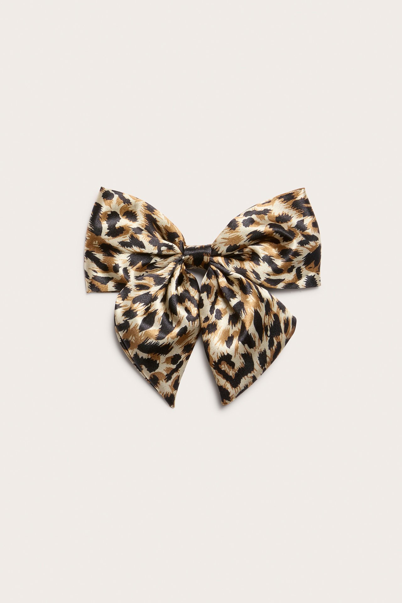 Framifrån, stor ljusbeige hårklämma i polyester med leopardmönstrad rosett.