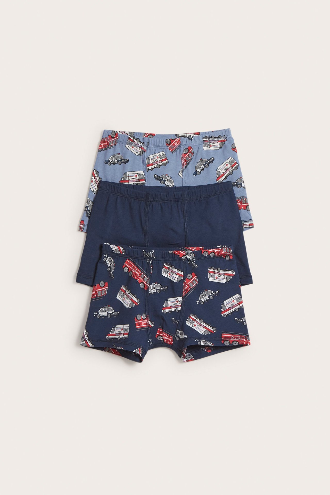 Frontvy av barnboxerkalsonger: mörkblå med fordonsmönster, enfärgad mörkblå och ljusblå mönstrad.