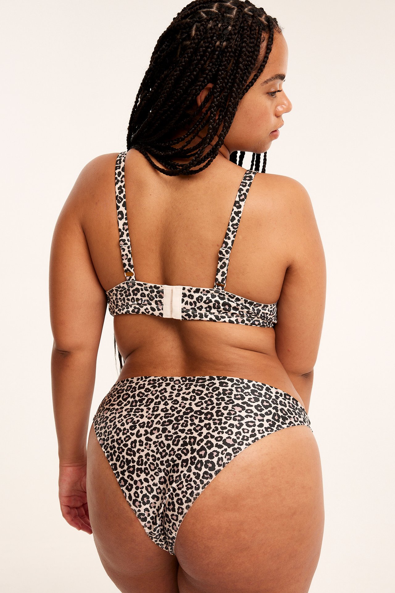 Bakifrån, kvinna i beige leopardmönstrad brazilian trosa och matchande behå.