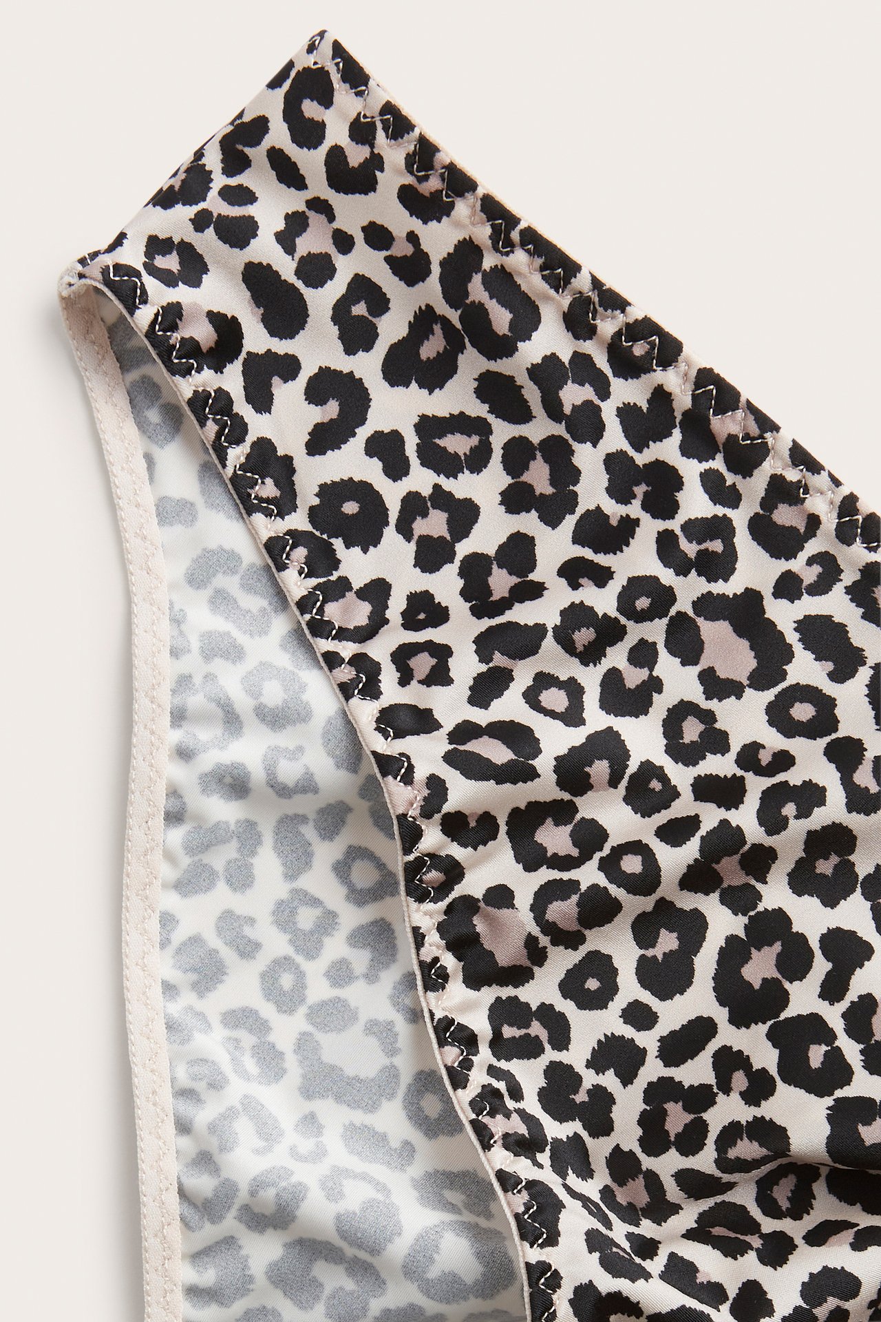 Närbild av en beige brazilian trosa i stretchig satin med leopardmönster.