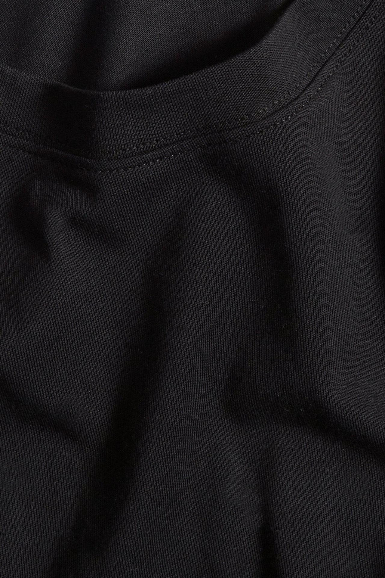 Zbliżenie czarnego, jednolitego bawełnianego t-shirtu, ukazujące fakturę materiału i dekolt.