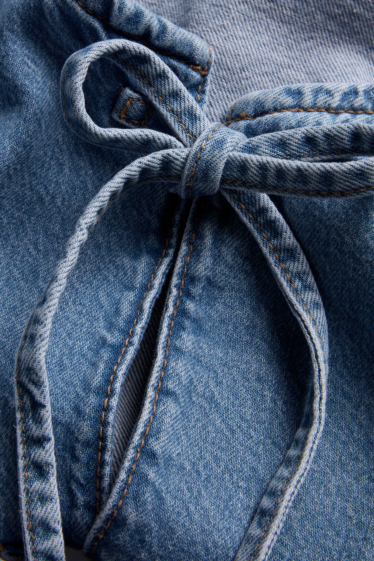 Lähikuva vaaleansinisestä naisten denim-puserosta, jossa on solmittu yksityiskohta edessä.