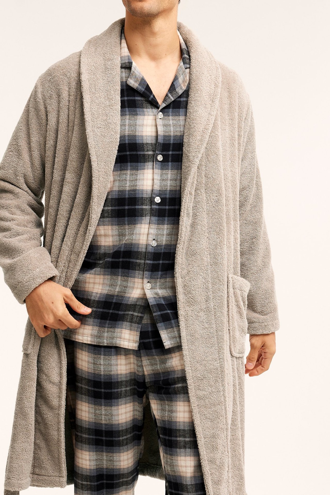 Etunäkymä: Mies avoimessa beigessä puuvillafrotee-kylpytakissa musta-beige ruudullisen pyjaman päällä.