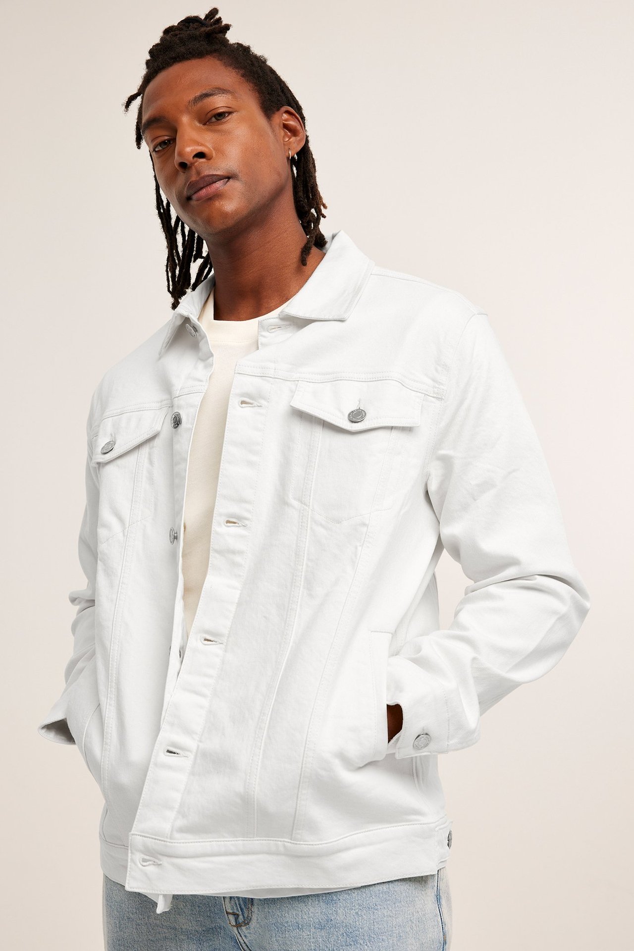 Edestäpäin, mies yllään vaalea beige twill-farkkutakki vaalean t-paidan ja vaaleansinisten farkkujen päällä.