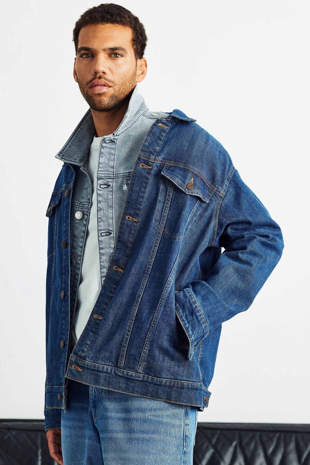 Mies, edestä näkymä tummansinisessä farkkutakissa, vaaleassa farkkupaidassa ja sinisissä farkuissa.