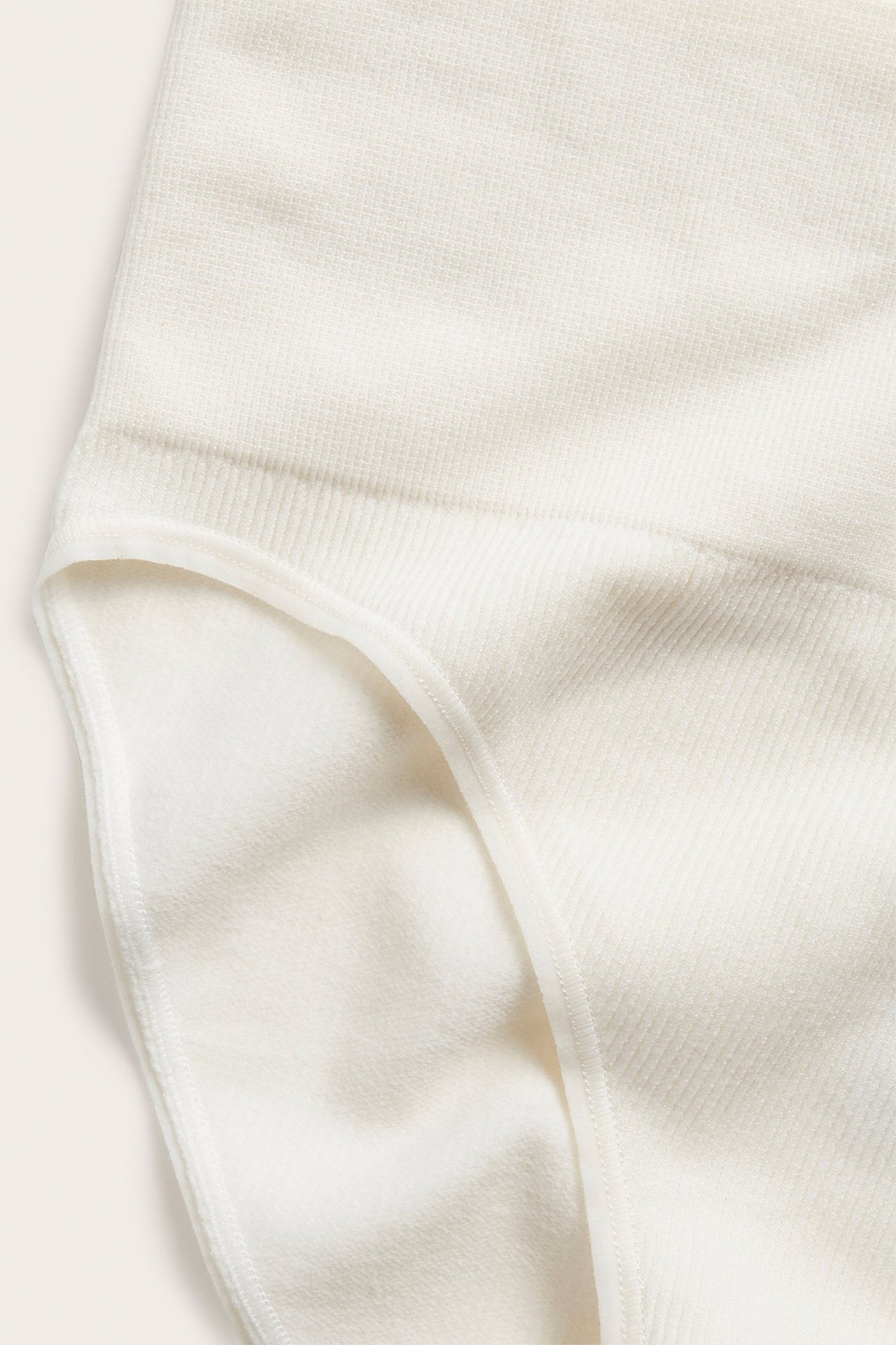 Zbliżenie białych, prążkowanych, bezszwowych majtek damskich typu brazilian ze strukturalnym wzorem.