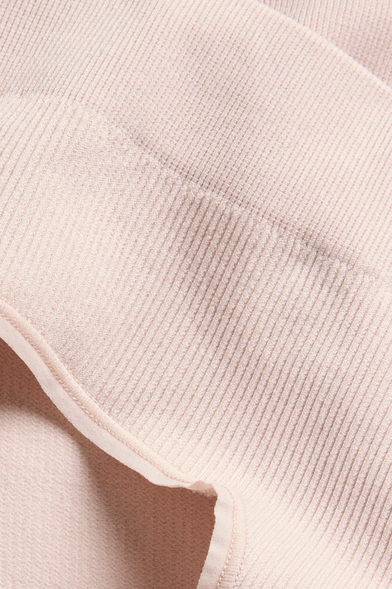 Zbliżenie jasnoróżowych, bezszwowych, prążkowanych stringów z wzorzystą fakturą.