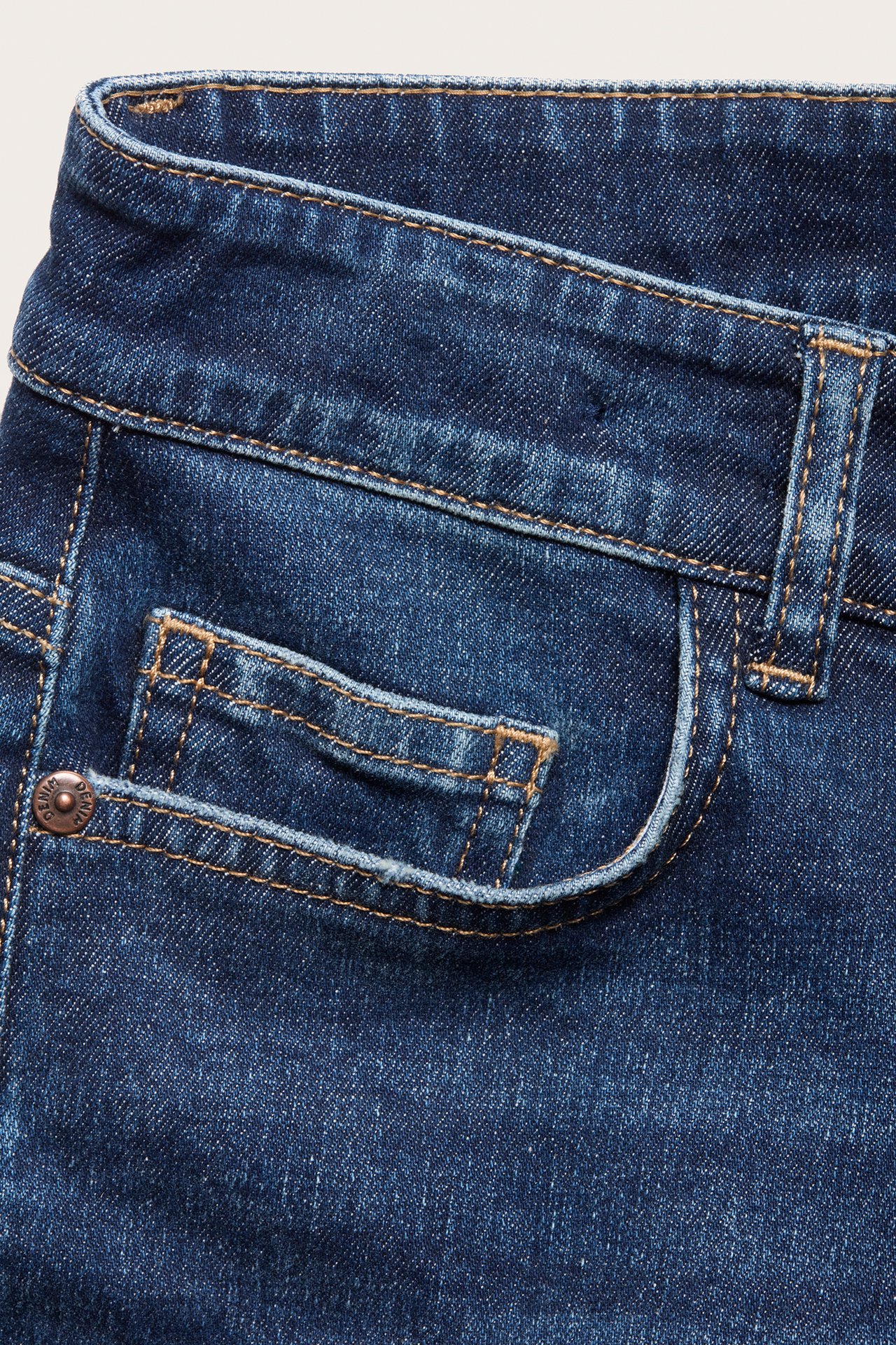 Zbliżenie na ciemnoniebieskie jeansy slim-fit z denimu z przednią kieszenią i widocznymi szwami.