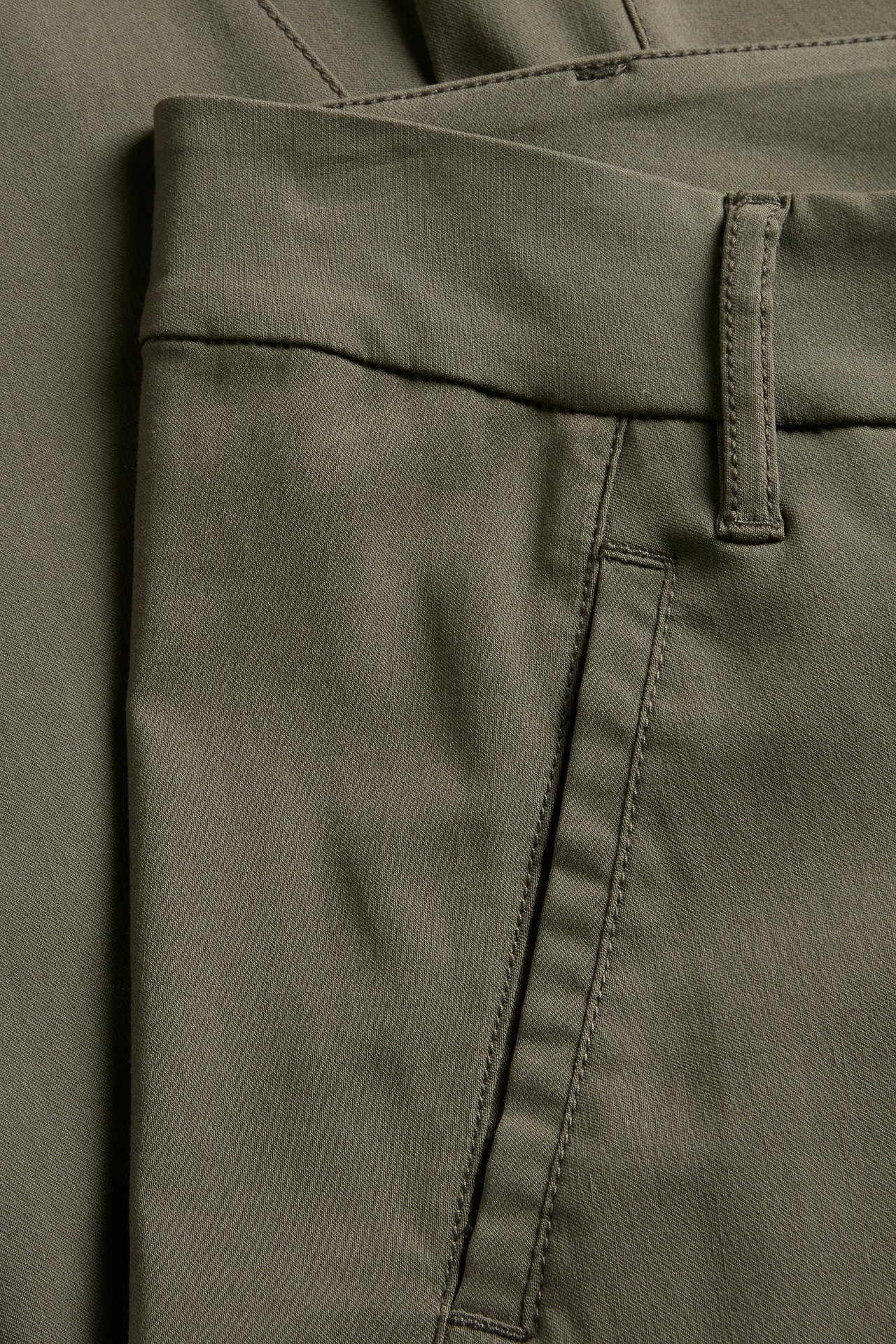 Lähikuva vihreistä slim fit boyfriend-housuista, joissa näkyy vyötärönauha, vyölenkki ja viisto tasku.