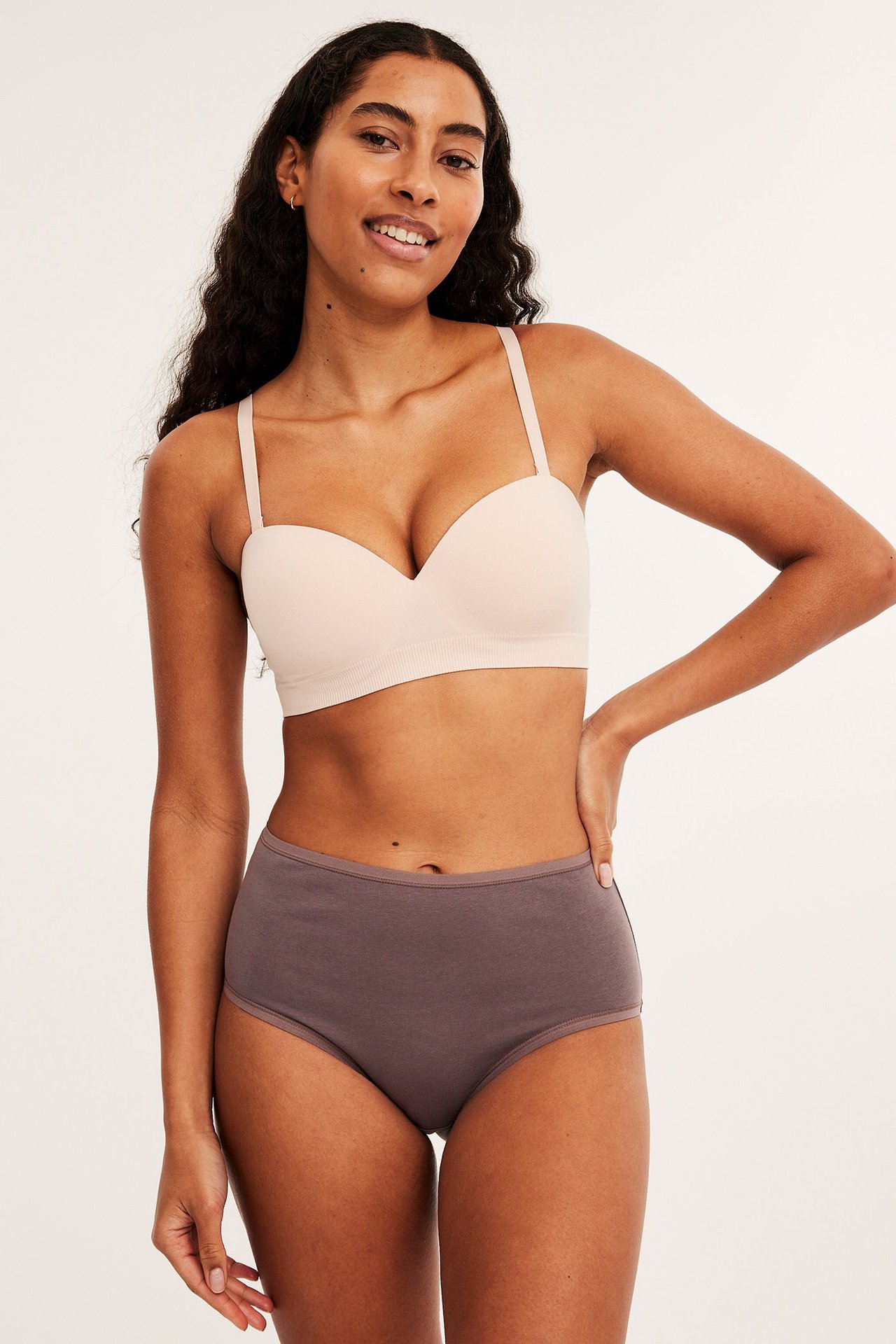 Forfra, kvinne i plommefargede høye bomullstruser og en lys beige BH.