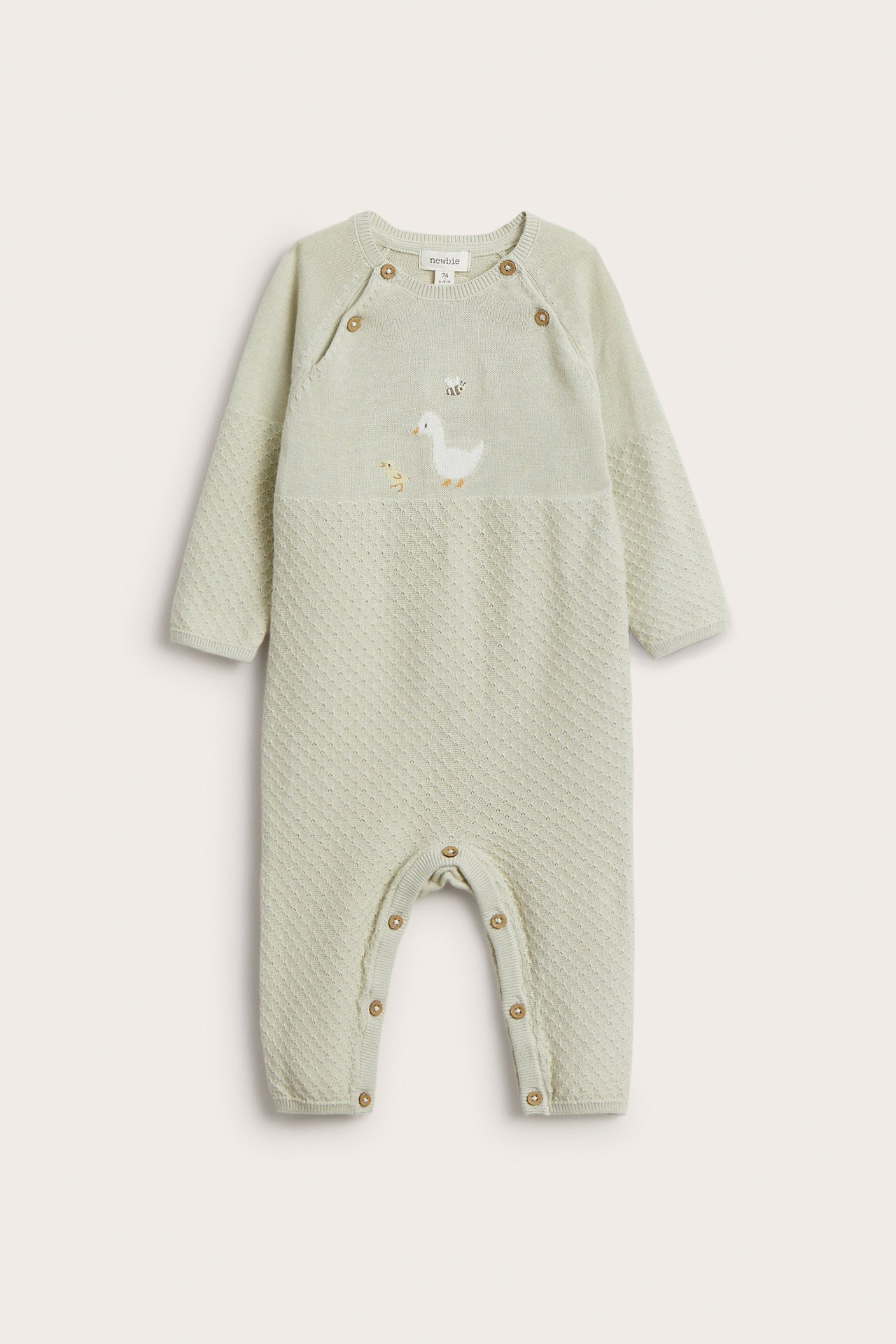 Frontvisning av en baby lys grønn strikket bomulls-coverall med andebroderi, skulderknapper og trykknapper i skrittet.