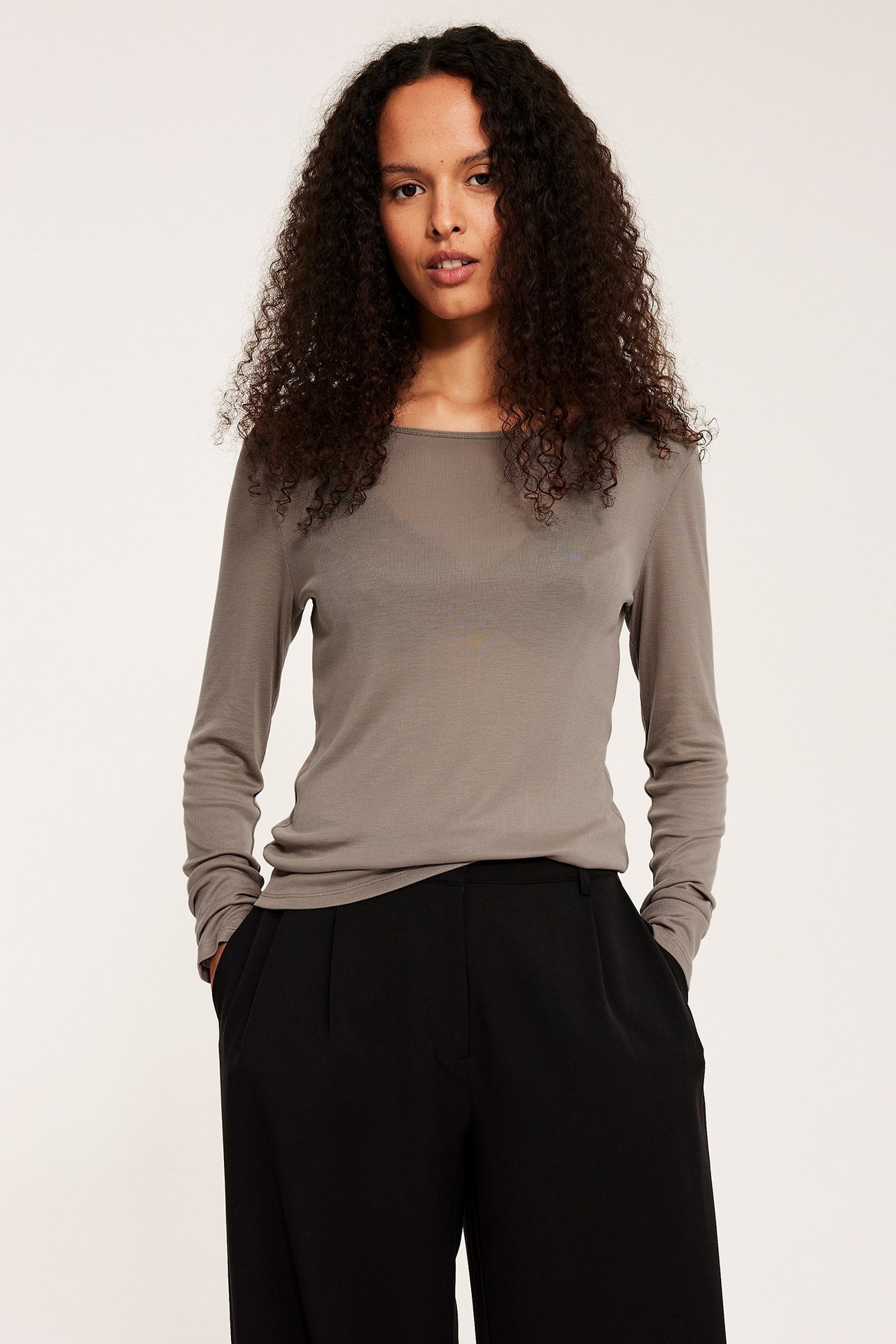 Widok z przodu: Kobieta w ciemnobeżowym topie z długim rękawem z lyocellu i czarnych szerokich spodniach.