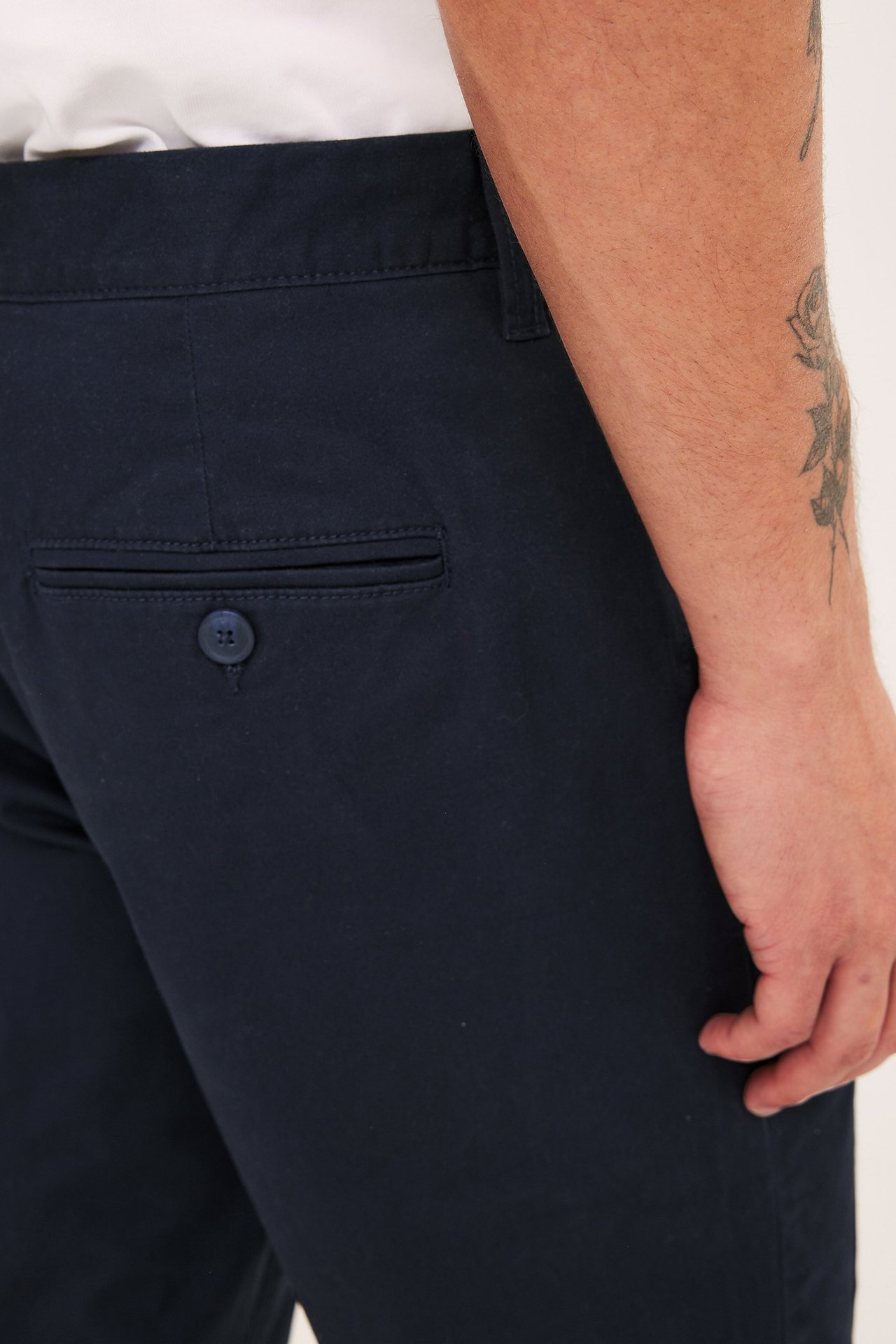Nærbilde av en manns mørkeblå regular fit bomullstwillchinos med en knappet baklomme.