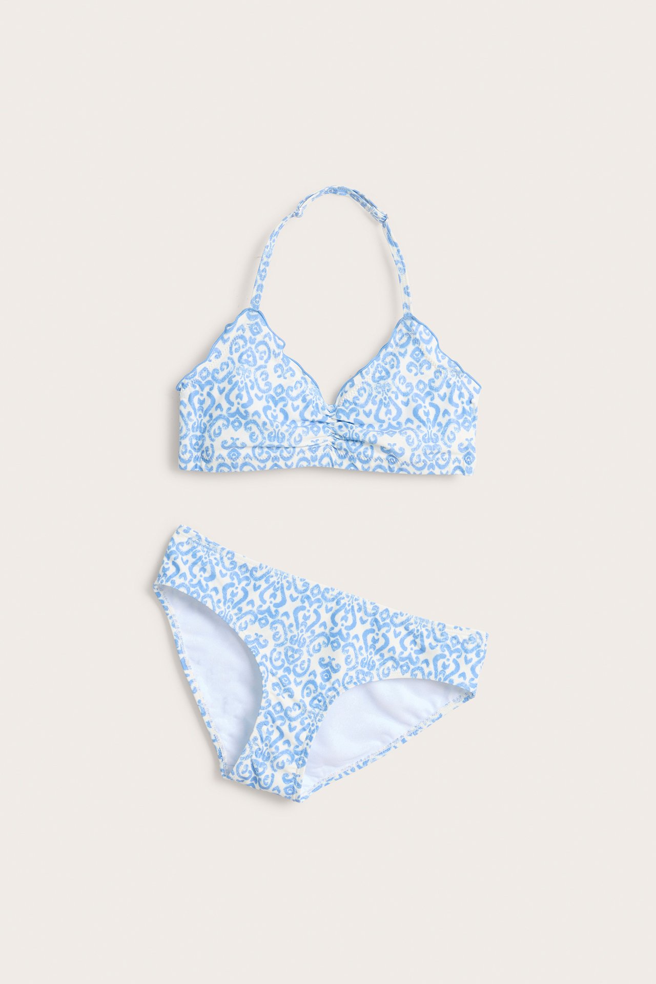 Framifrån, offwhite och ljusblå mönstrad halterneckbikini med babylock-kanter.