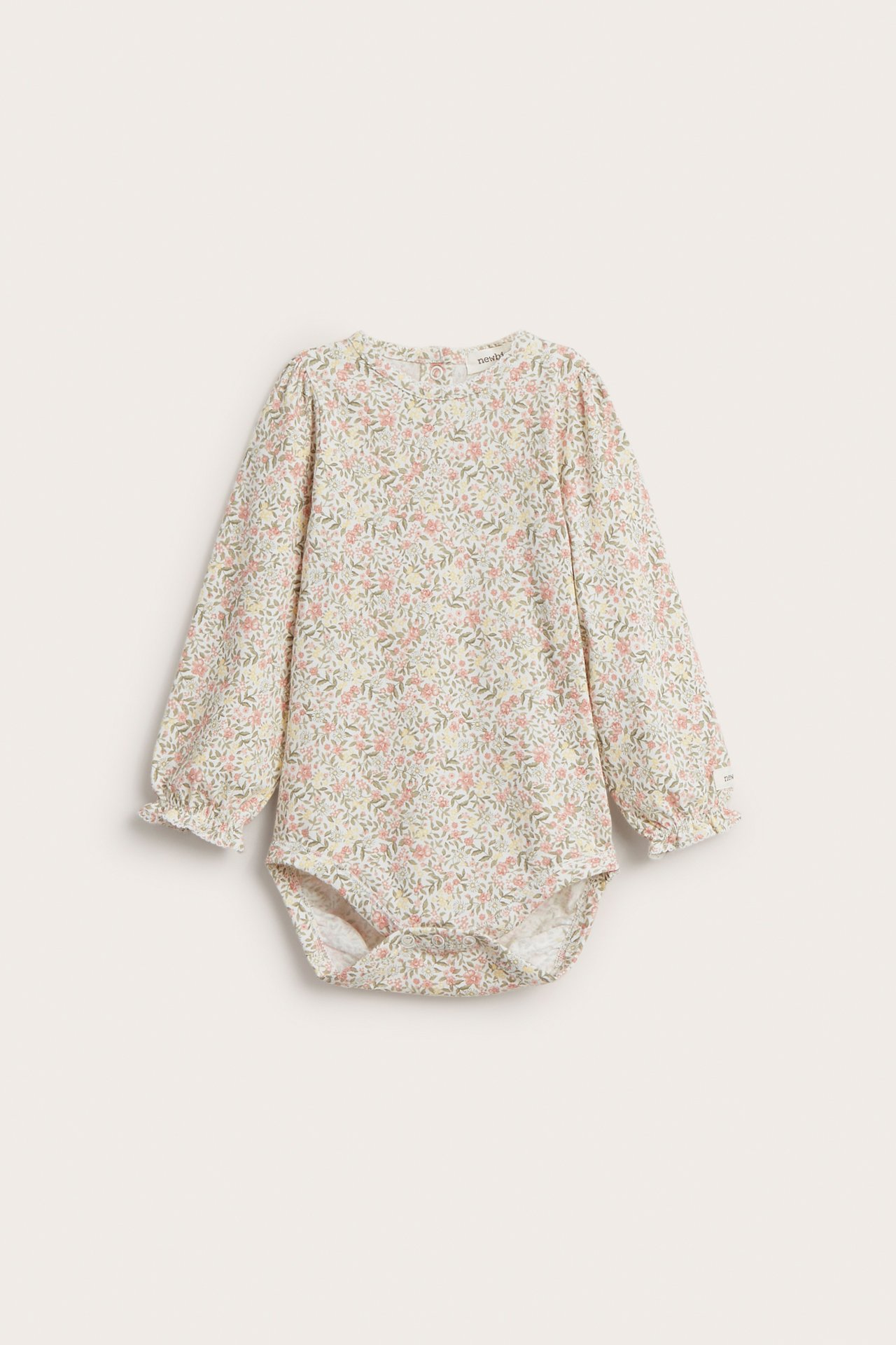 Frontvisning av en offwhite blomstret langermet jerseybody til baby med volangkantede mansjetter og picotkant.