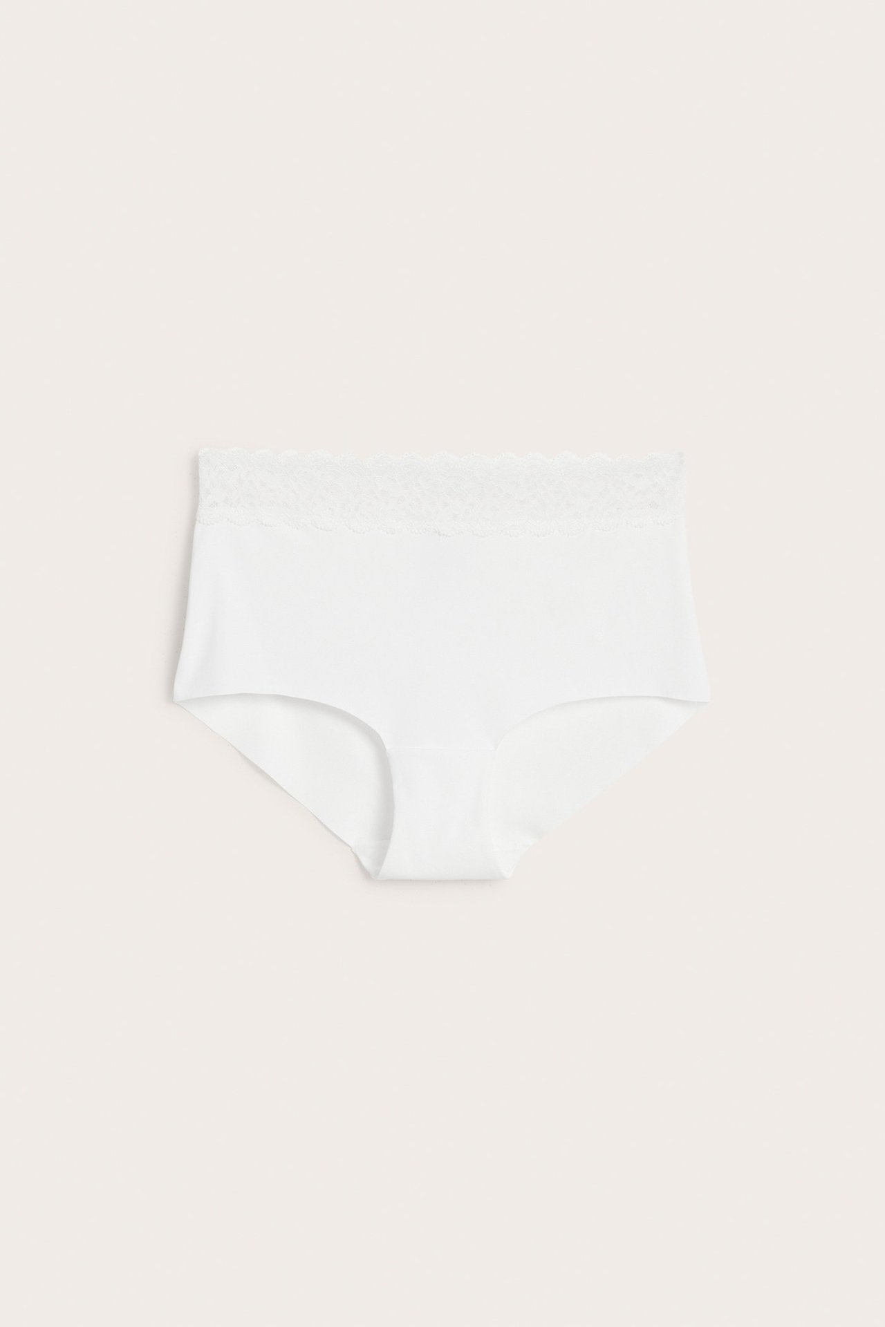 Frontvisning av hvite, ensfargede hipster-truser med middels høy midje og myk blondekant i midjen.