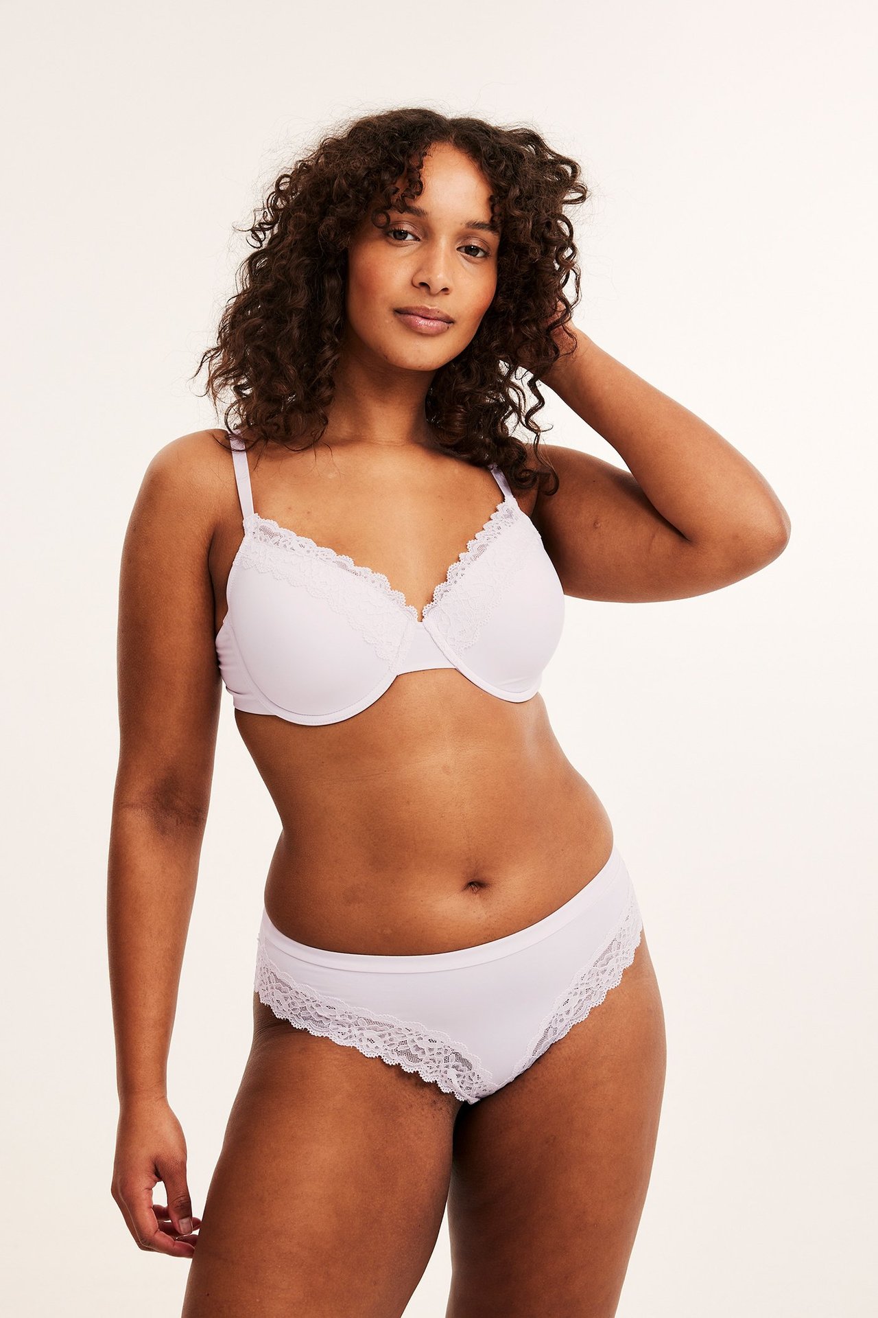 Forfra, kvinne i hvit micro brazilian truse med blonde og matchende BH.