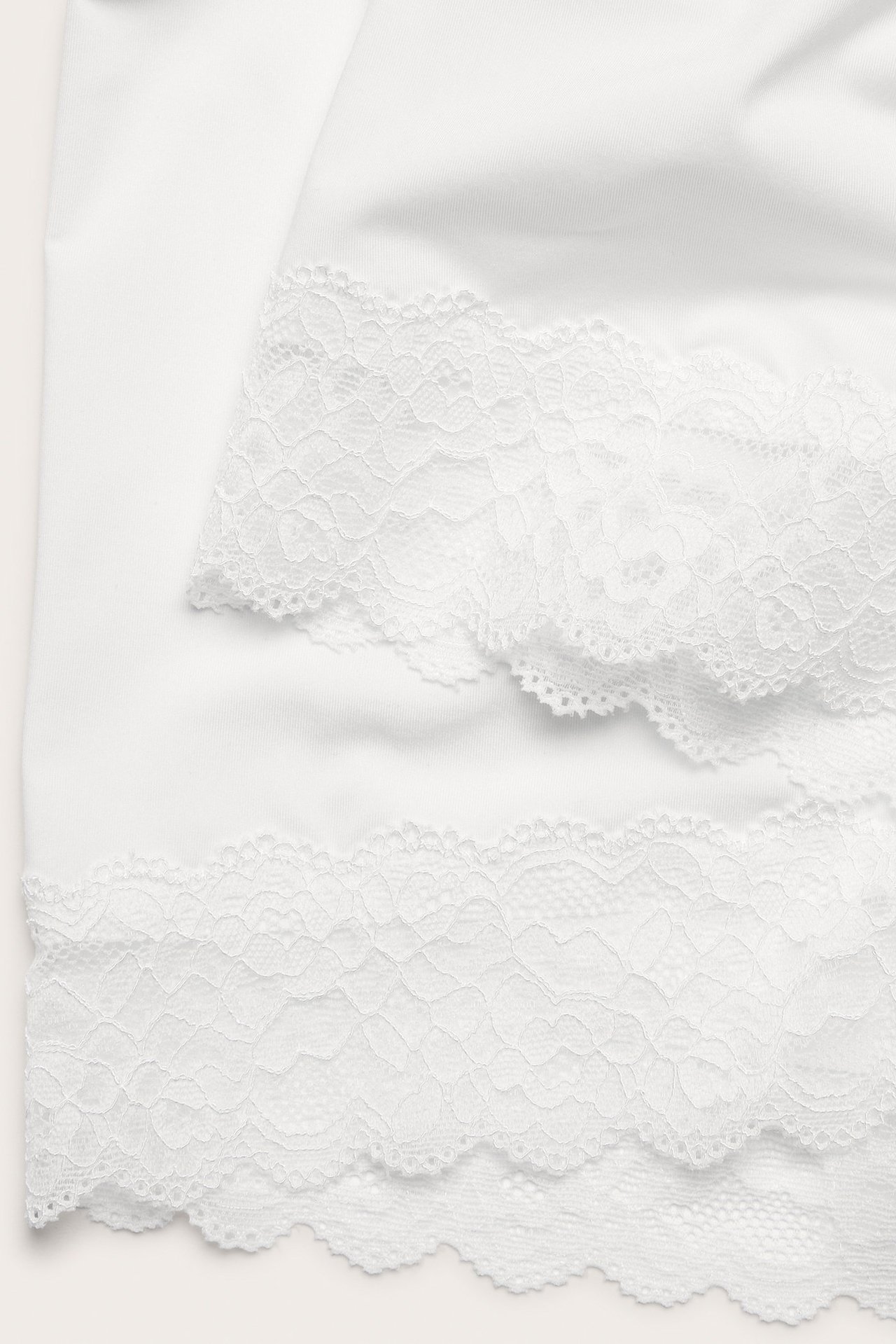 Zbliżenie białych mikroszortów z delikatną koronkową krawędzią.