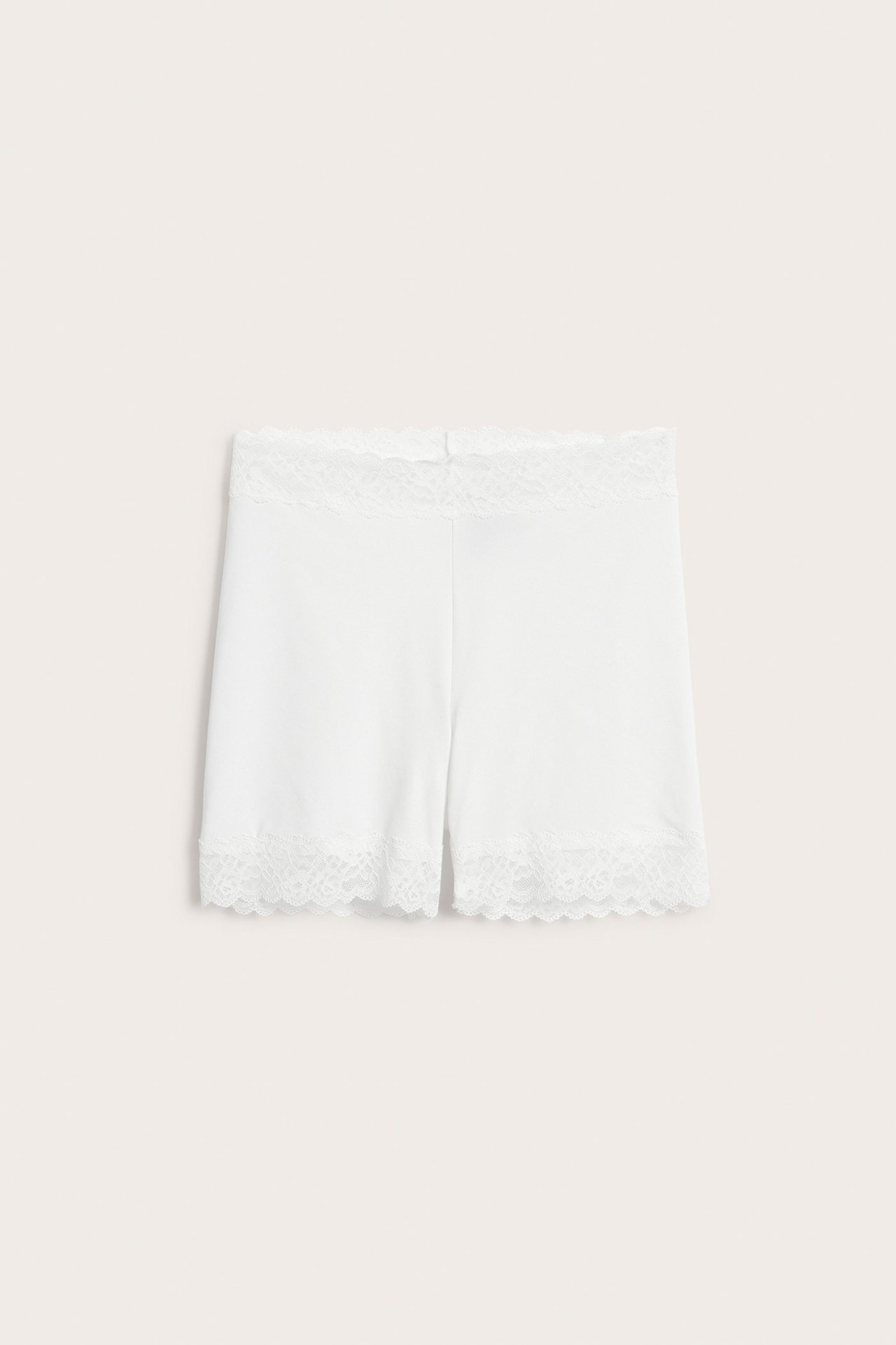 Frontvisning av hvite mikroshorts med delikat blondekant i midjen og benåpningene.