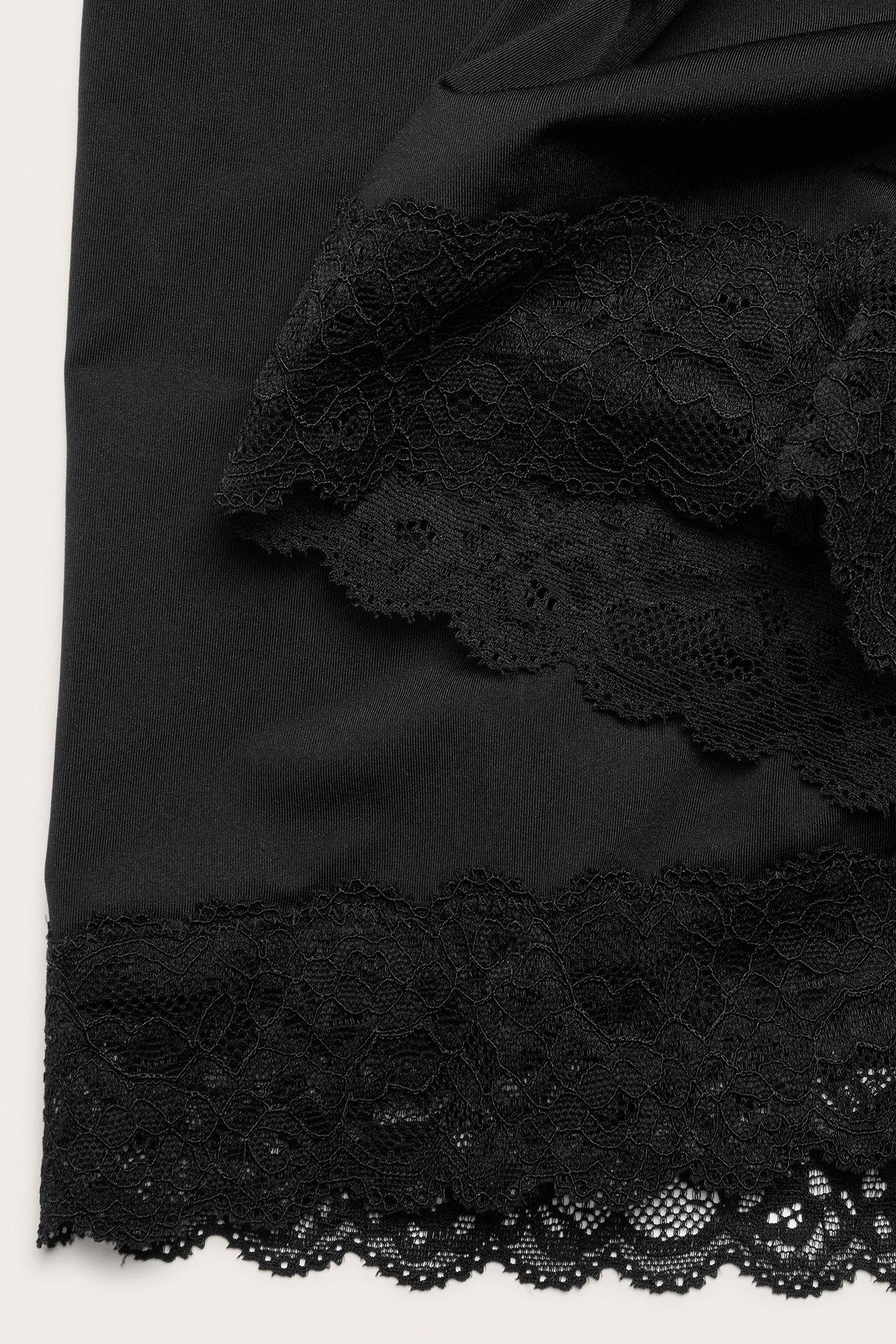 Zbliżenie na czarne mikroszorty z delikatną koronkową lamówką wzdłuż krawędzi.