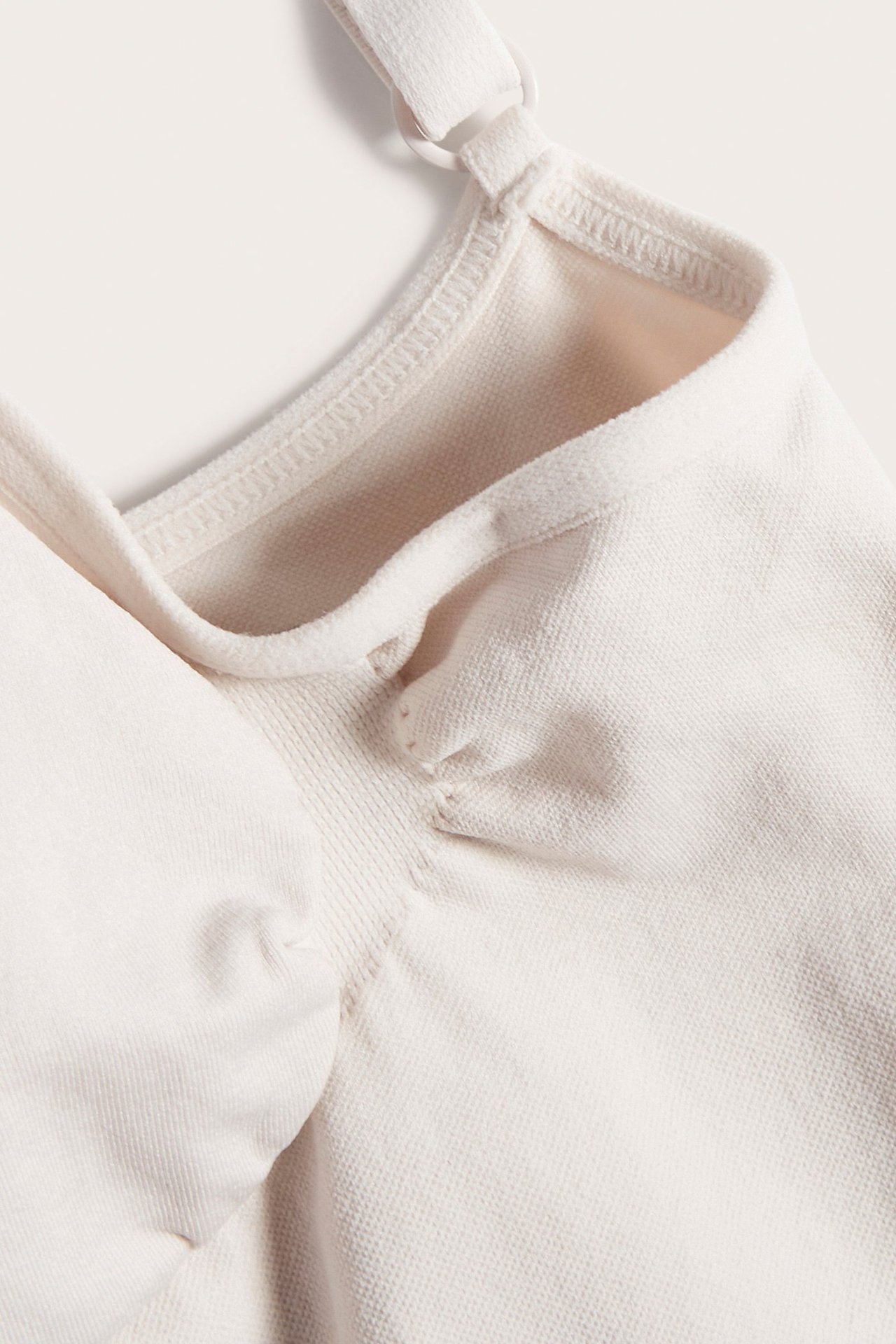 Zbliżenie beżowego, bezszwowego body modelującego z regulowanymi ramiączkami.