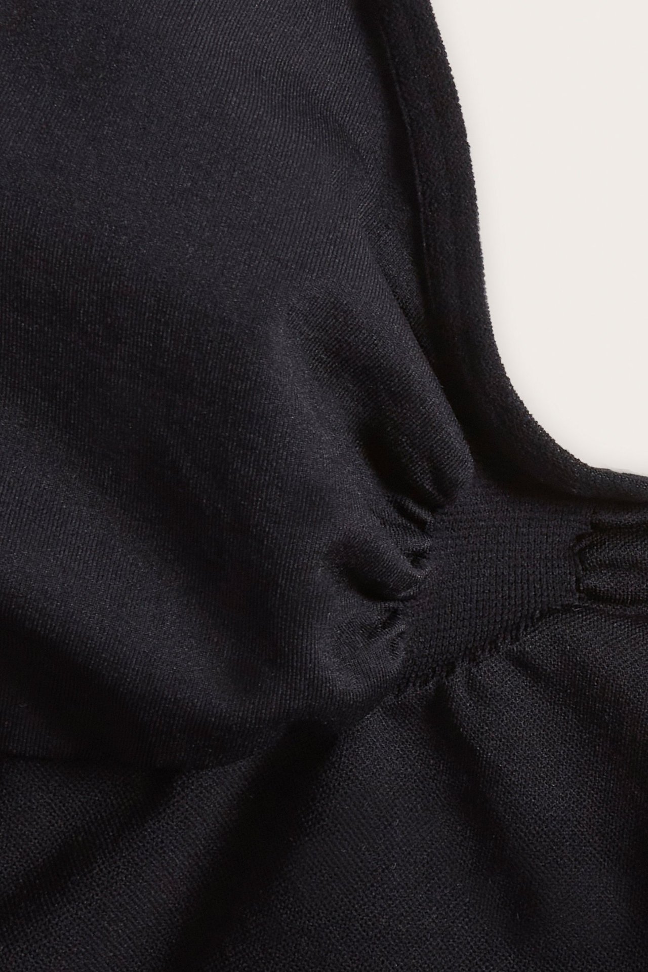 Zbliżenie czarnego, bezszwowego body modelującego z marszczonym detalem na tkaninie.