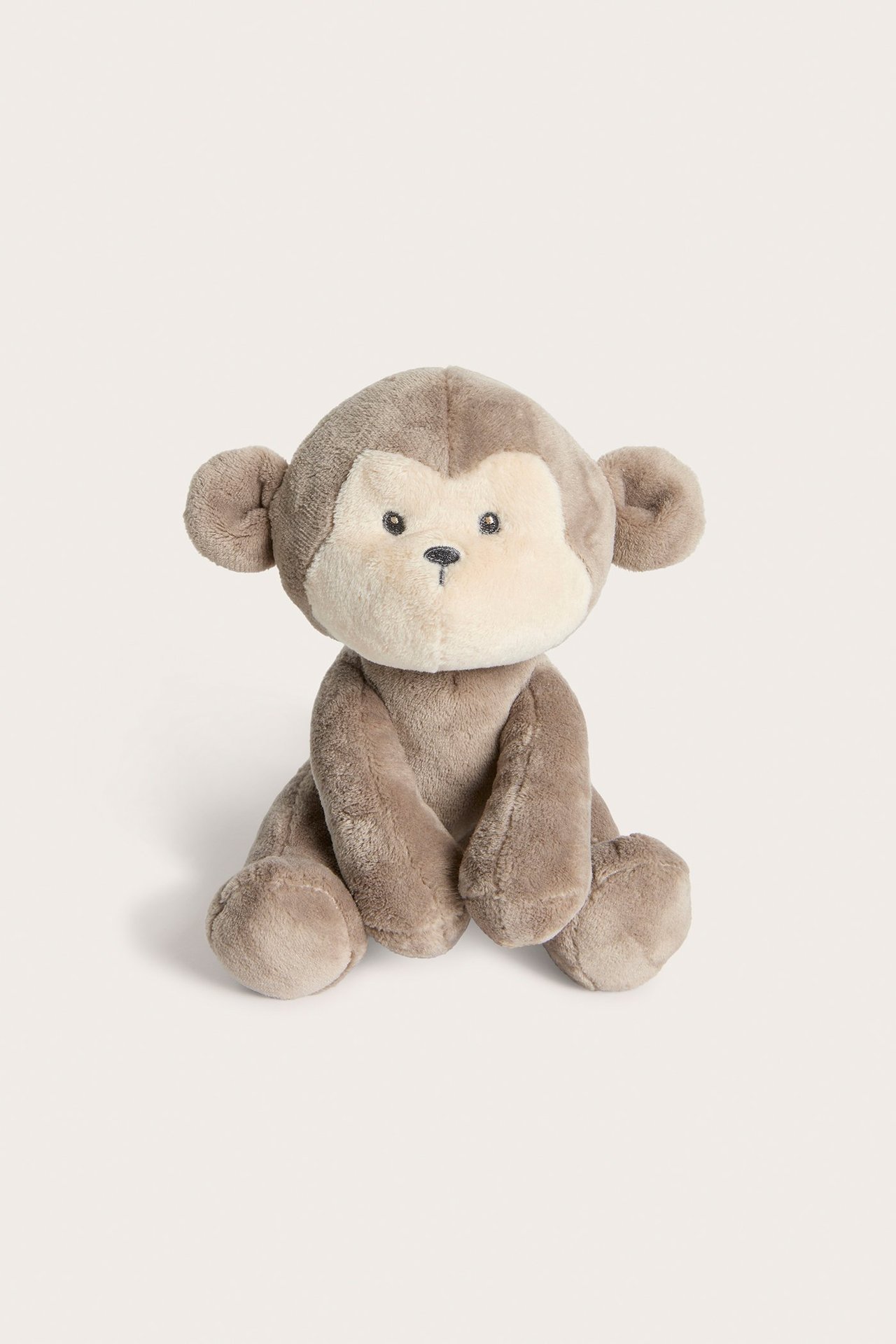 Framifrån, en mjuk brun plyschapa med ljusbeige ansikte, sittande.