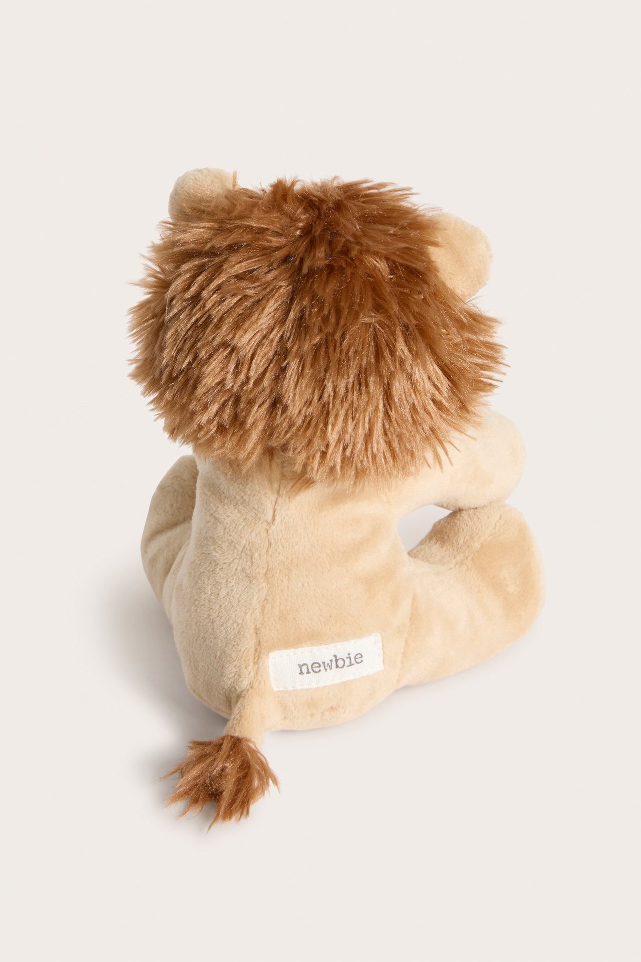 Bakifrån av ett beige mjukisdjur lejon med brun man och svans, med en 'newbie'-etikett.