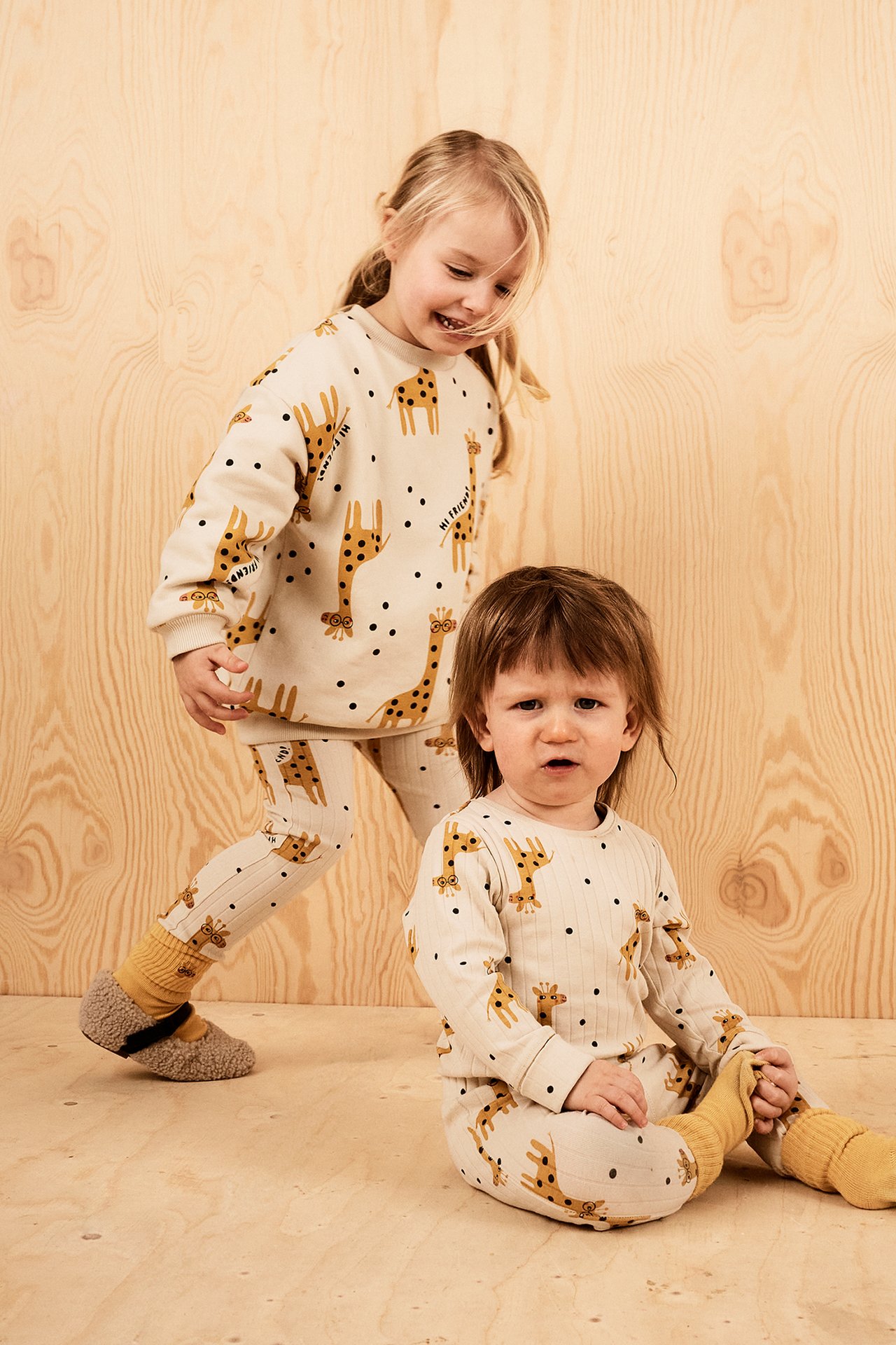 Framifrån, två barn i beiga ribbade leggings med giraffprint och matchande långärmade tröjor.