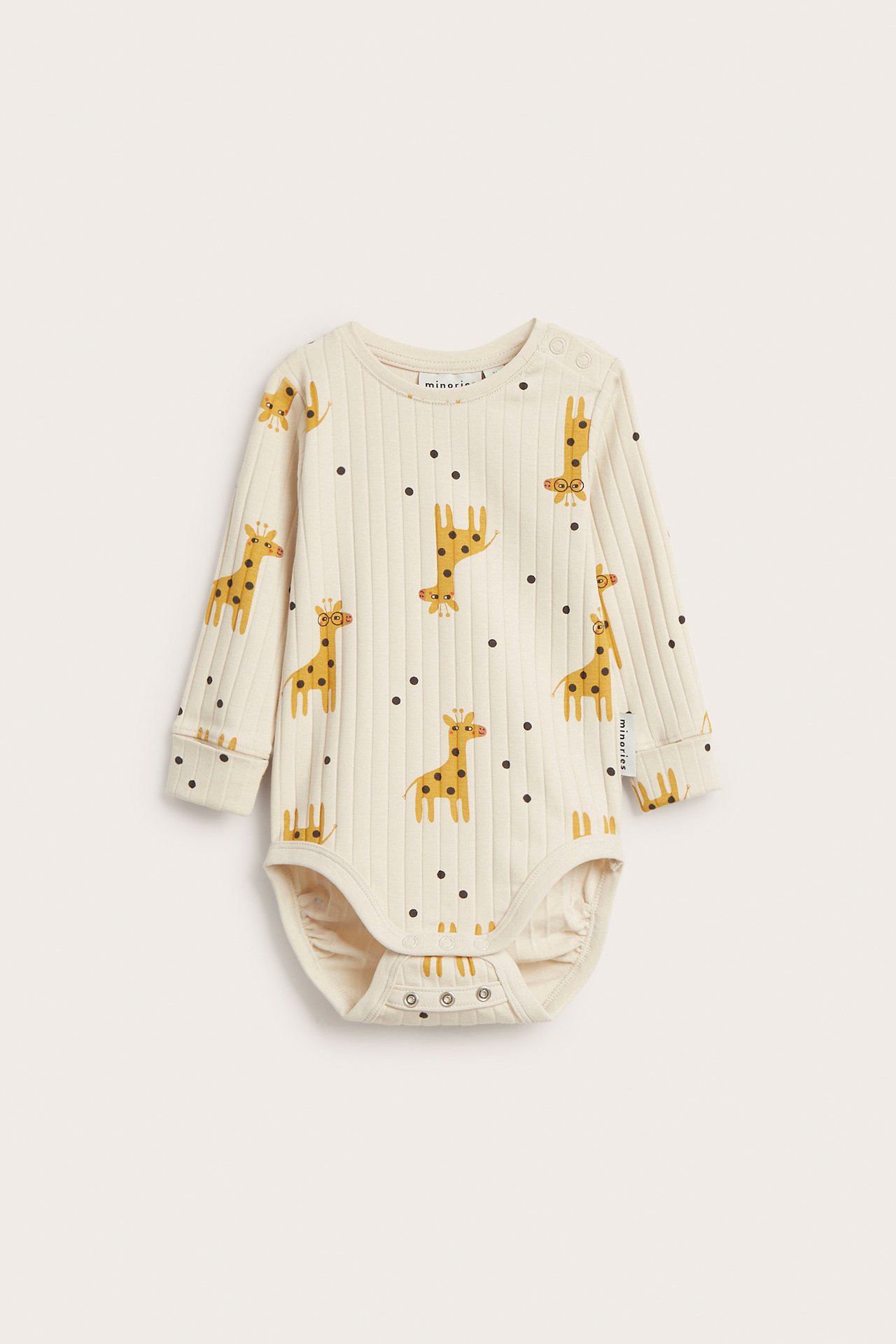 Frontvy av en beige ribbad långärmad babybody med giraff- och prickmönster, tryckknappar.