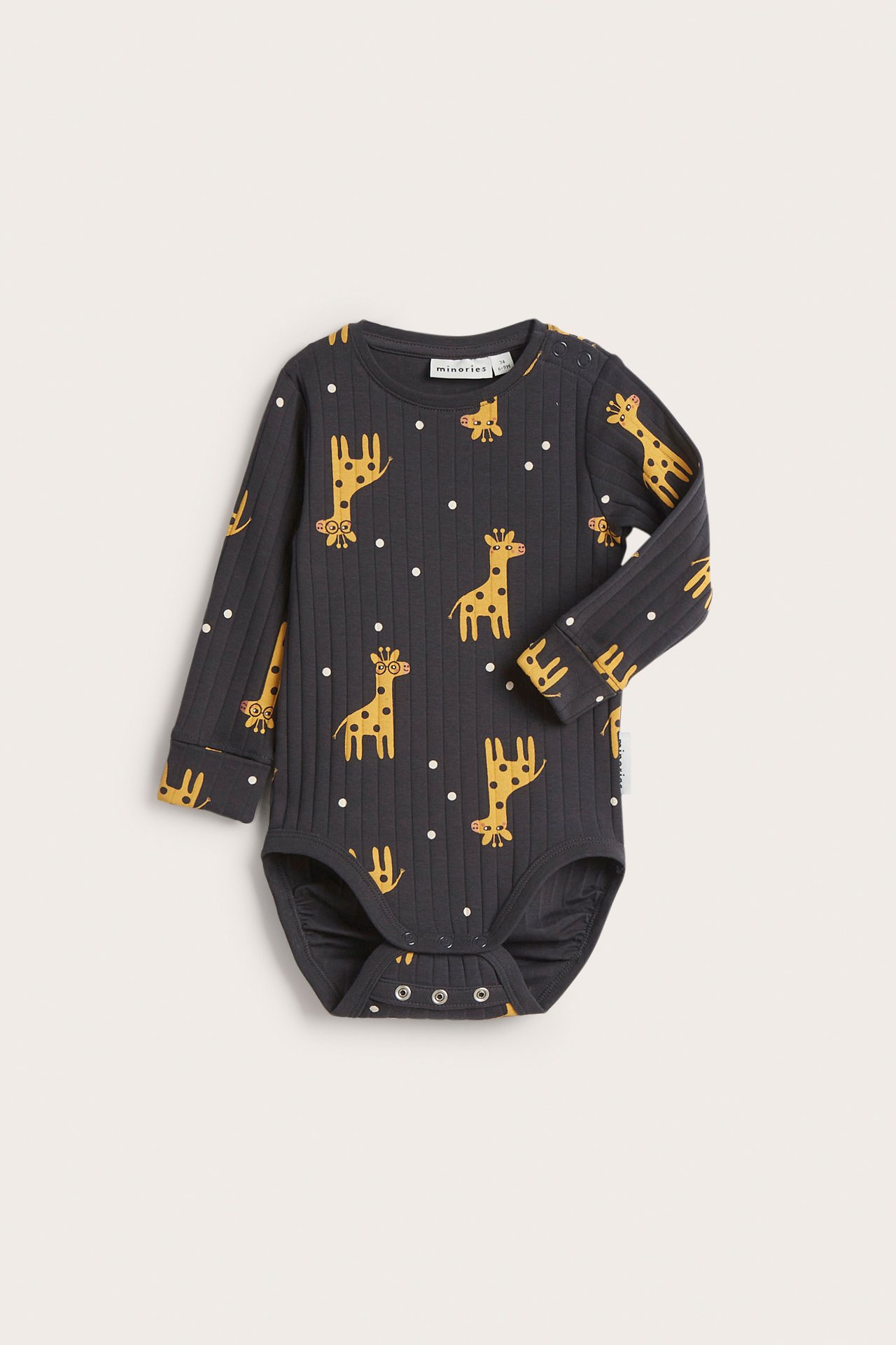 Frontvy: Babyns mörkgrå ribbade body med gult giraff- och vitt prickmönster, tryckknappar.